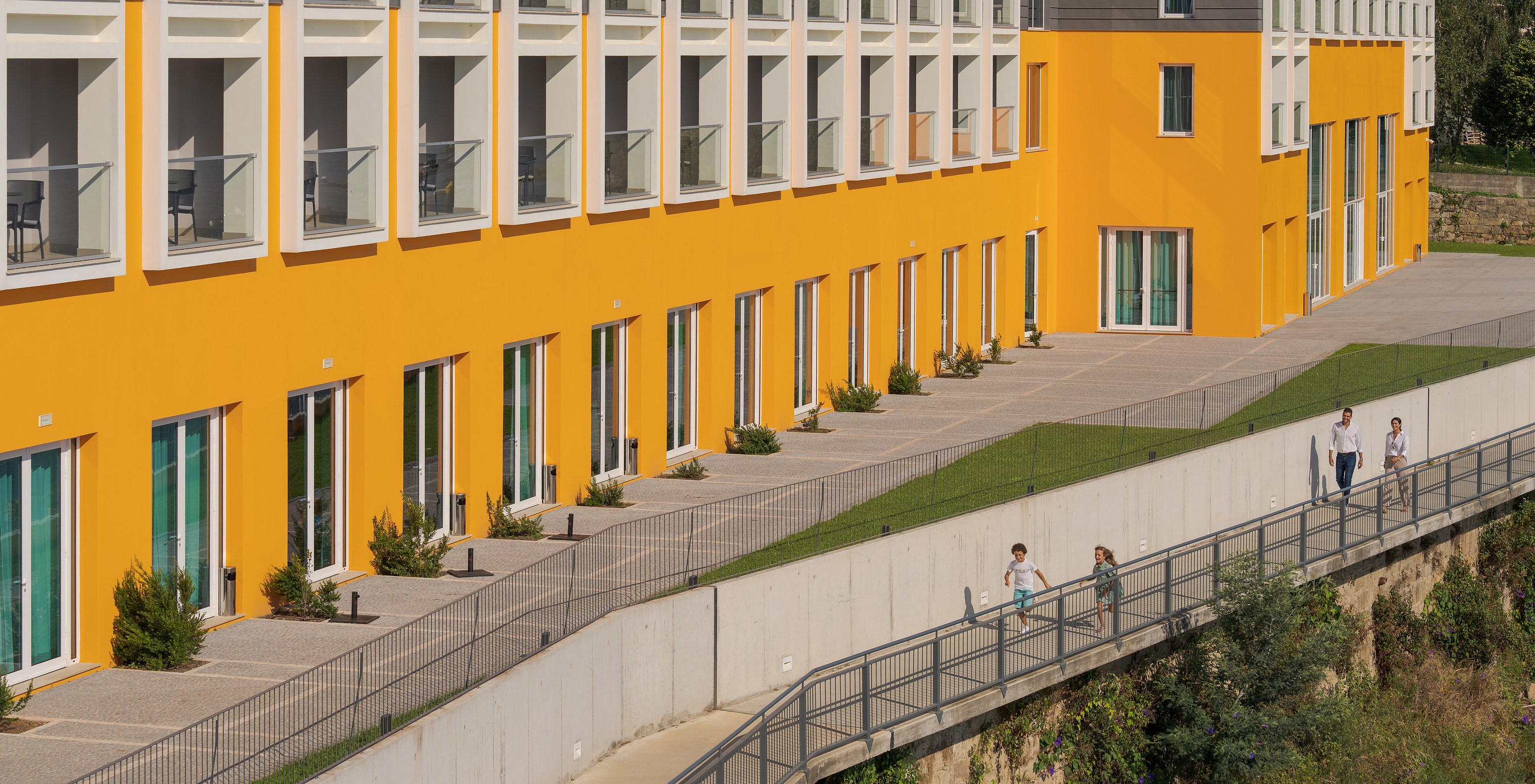 Blick auf die Fassade des Pestana Douro, wo mehrere Balkone des Hotels und Kinder, die am Deich laufen, sichtbar sind