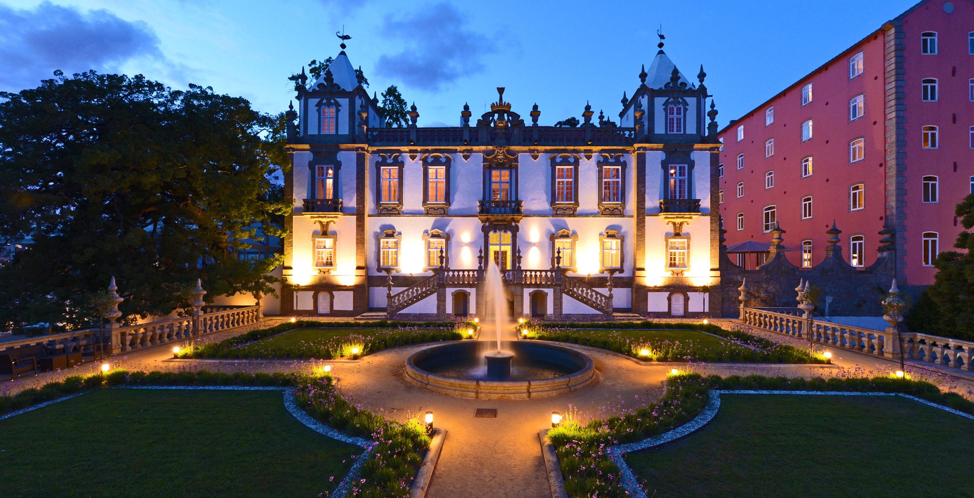 Fassade des Pestana Palácio do Freixo bei Nacht, ein imposantes, beleuchtetes Palast mit einem gepflegten Garten drumherum