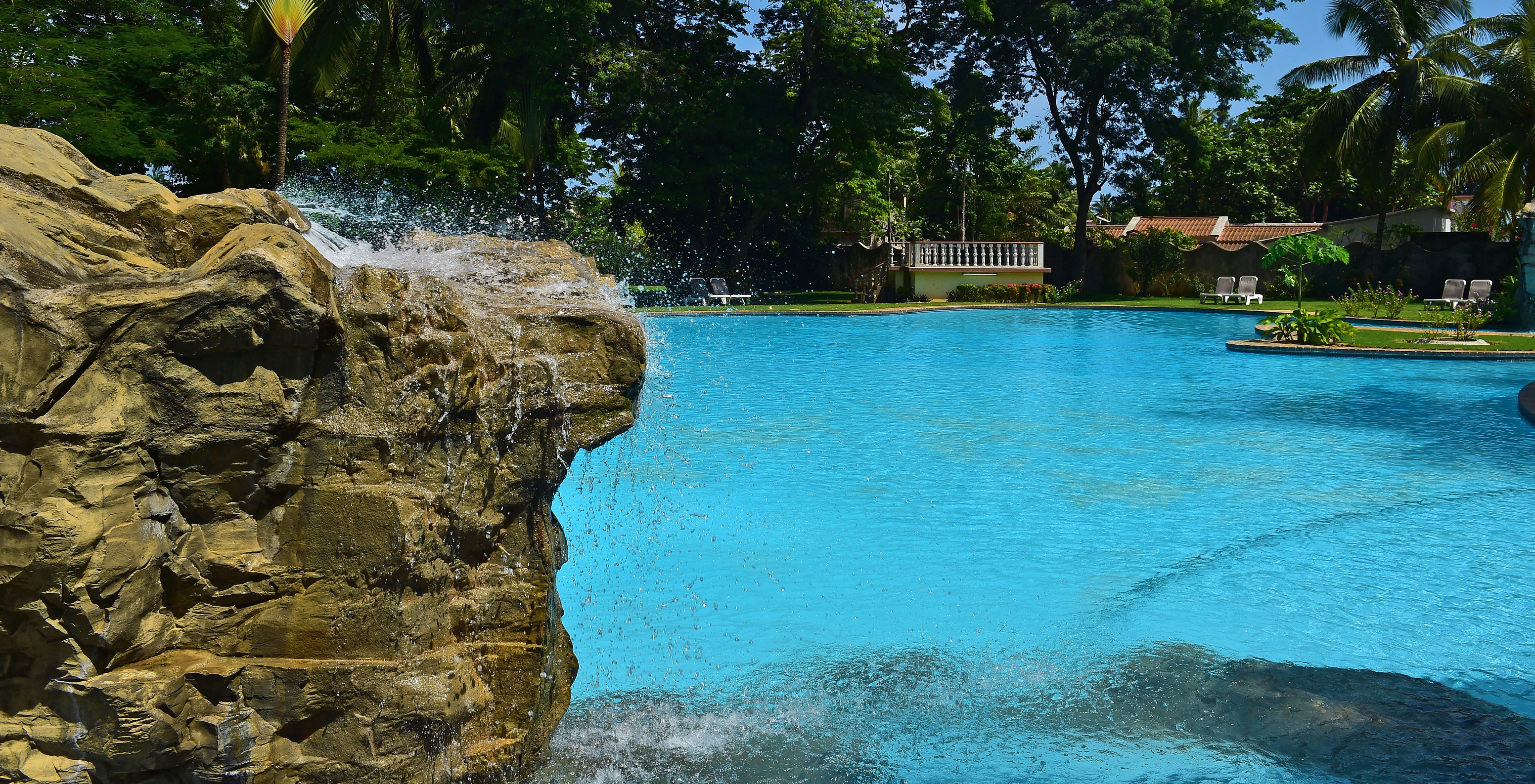 Außenpool des Pestana Miramar São Tomé, mit blauem Wasser, das den klaren Himmel widerspiegelt und Liegen im Hintergrund