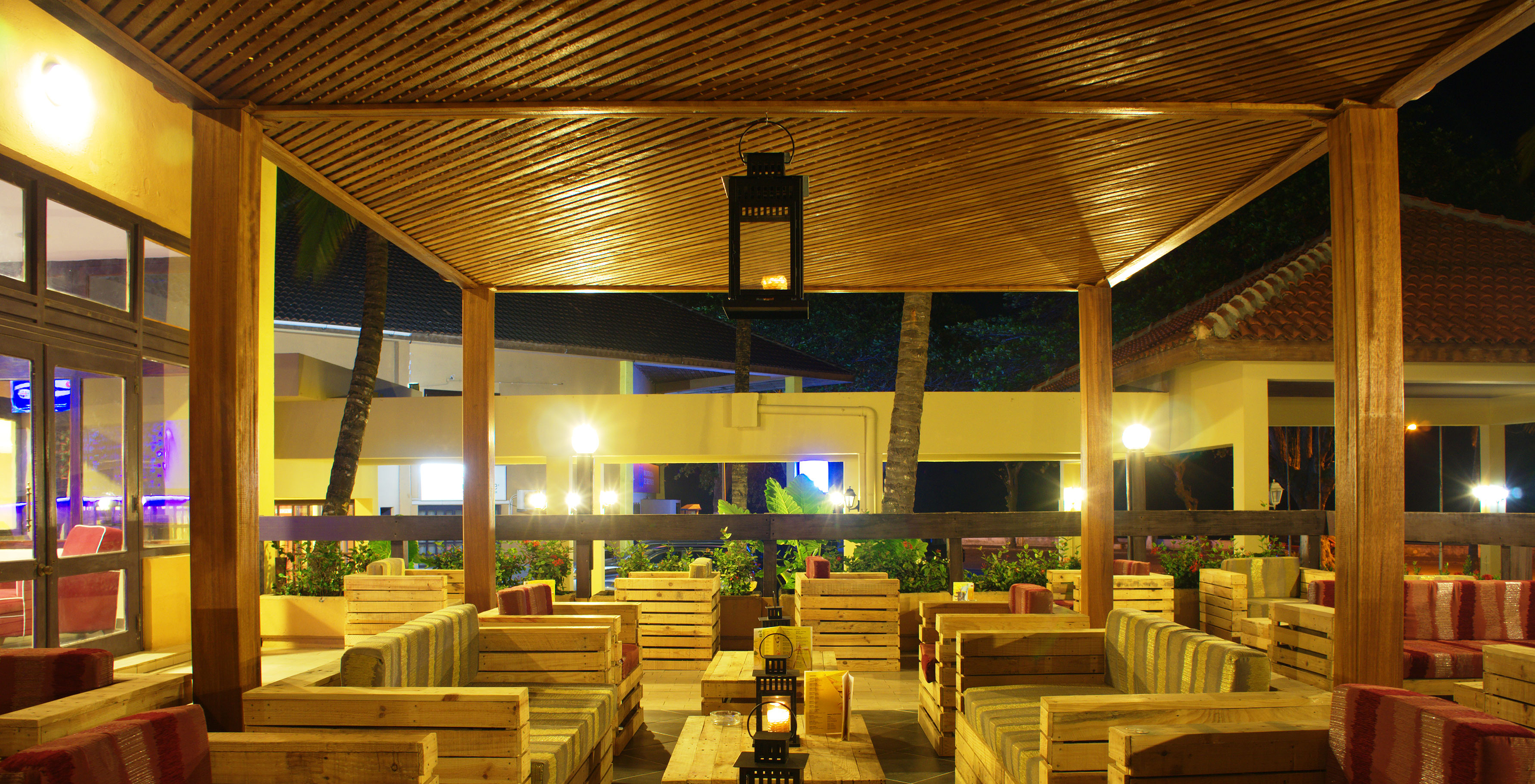 Die Bar Safu, im 4-Sterne-Hotel in São Tomé, hat mehrere Tische mit Holzmöbeln und bunten Kissen