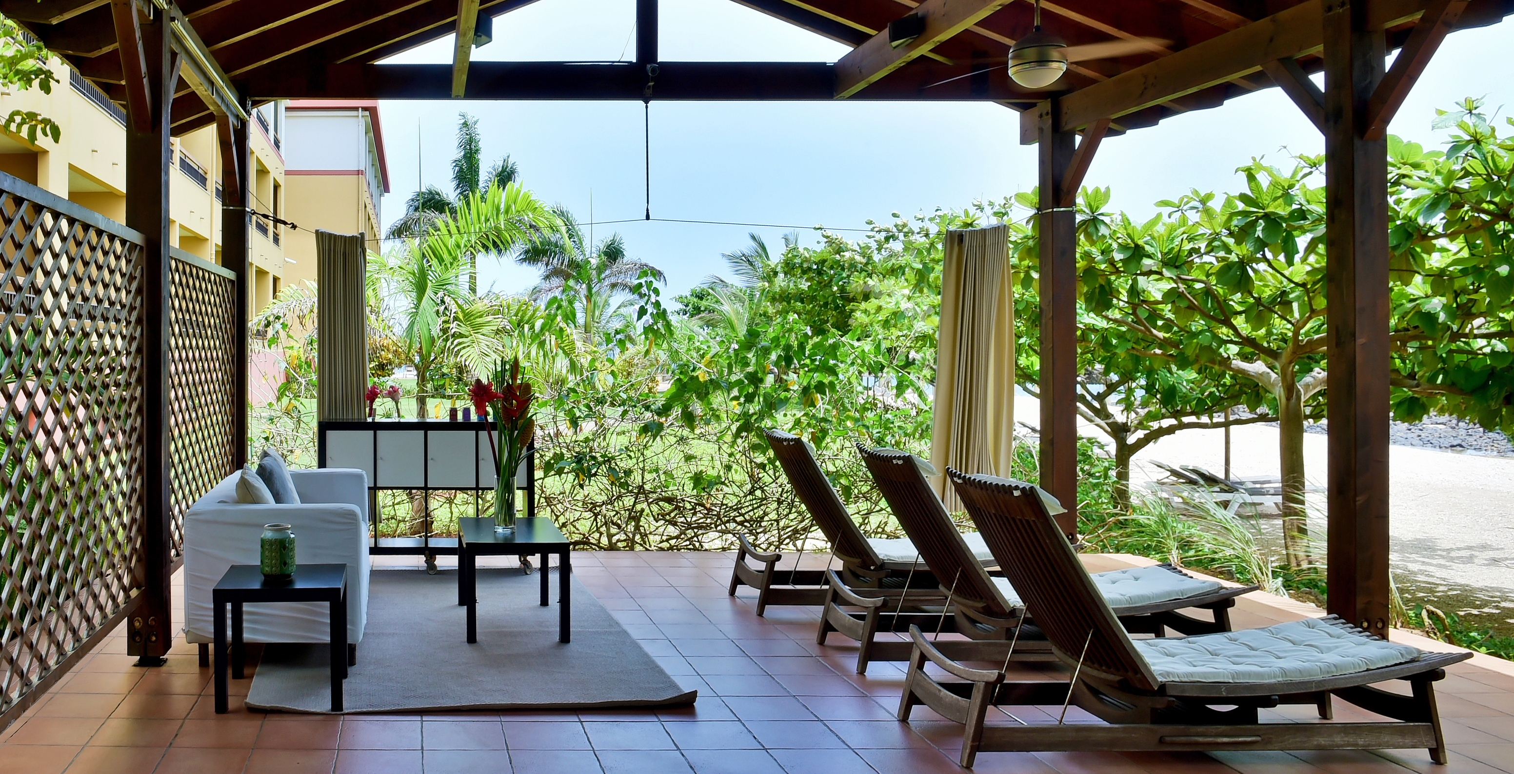 Überdachter Außenbereich des 5-Sterne-Hotels in São Tomé, mit einem Sofa und Strandstühlen mit Meerblick