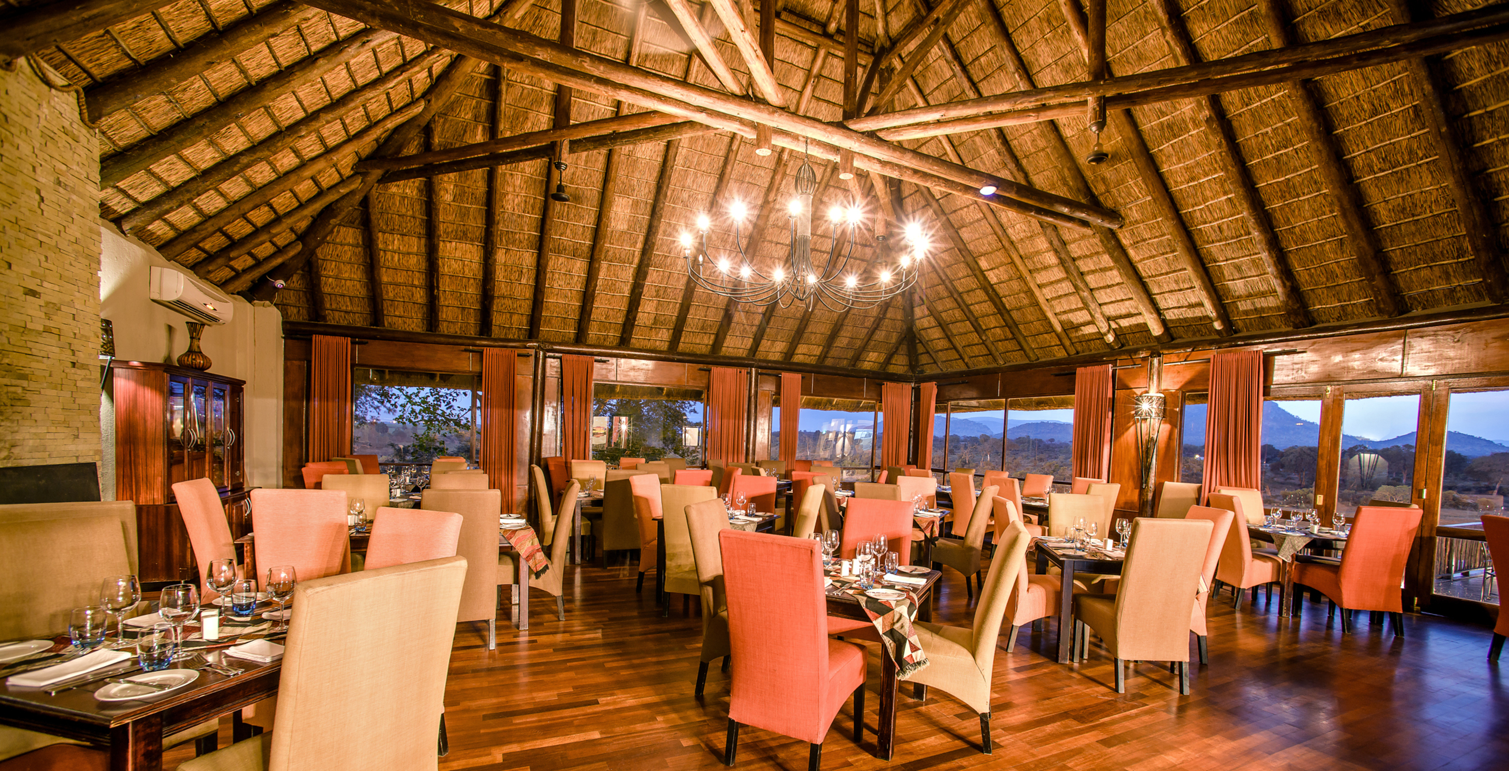 Das Restaurant Buhlebethu, im 4-Sterne-Hotel im Kruger Park, hat mehrere Tische und eine typisch afrikanische Dekoration