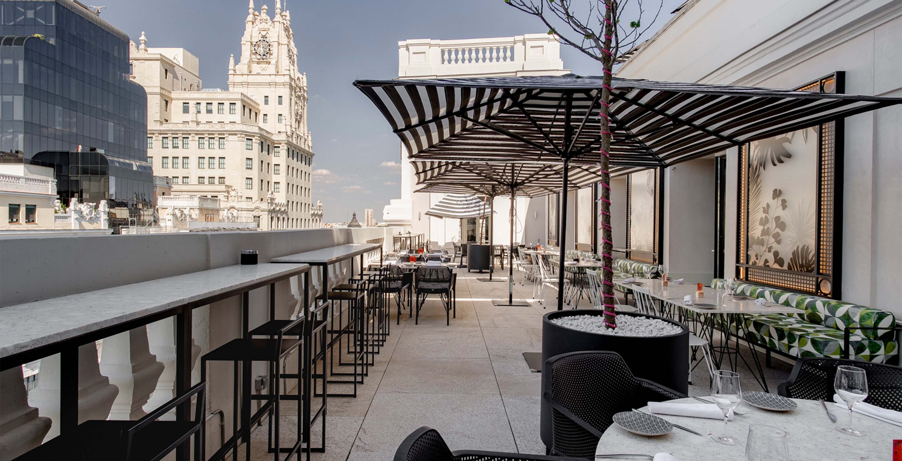 Restaurant im Rooftop mit Tischen, Stühlen und Blick auf die Gebäude der Gran Vía