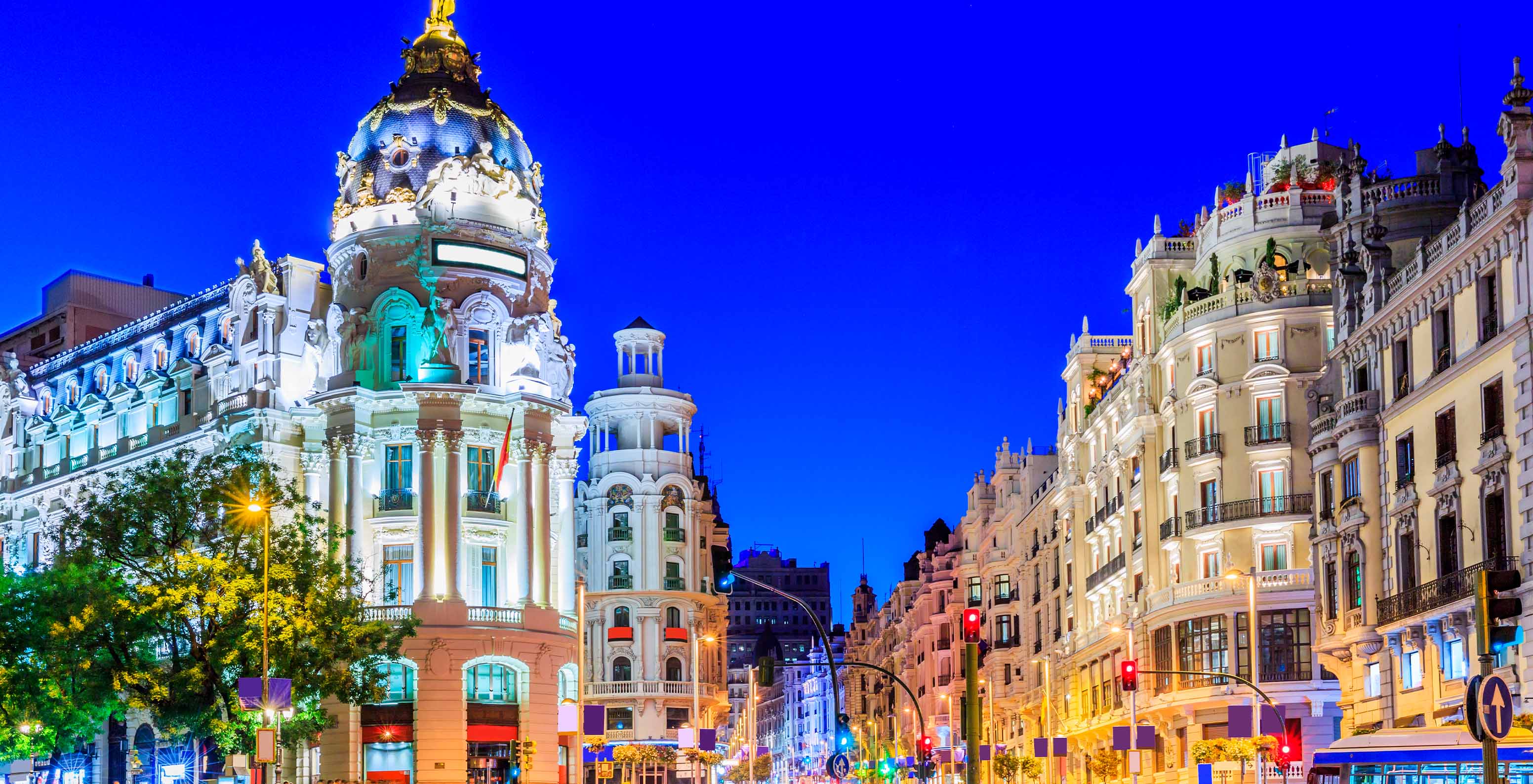 Blick auf die Gran Vía mit ikonischen Gebäuden, Autos und Lichtern im Stadtzentrum