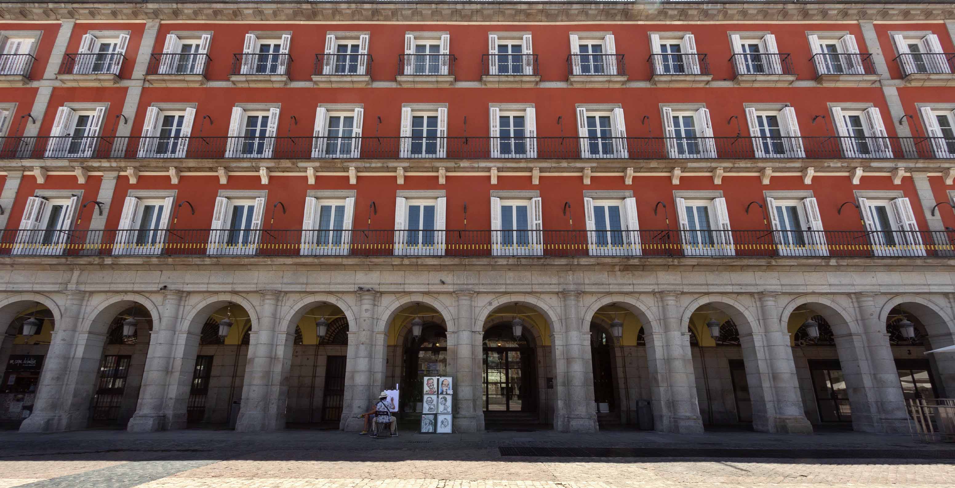 Blick auf die Fassade des Gebäudes des Pestana Plaza Mayor Madrid, tagsüber, in Rottönen und mit mehreren Fenstern