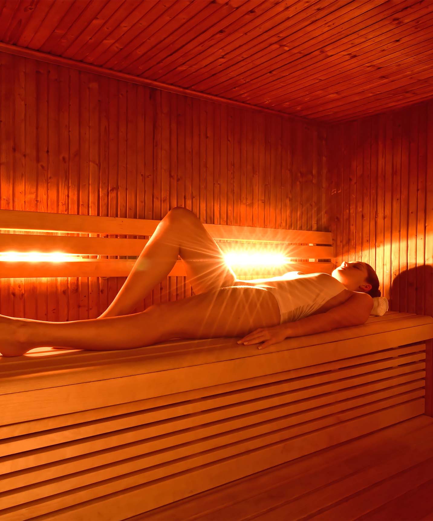 Spa des Hotels Pestana Chelsea Bridge mit einer Frau, die in der Sauna liegt und sich mit orangefarbenem Licht entspannt