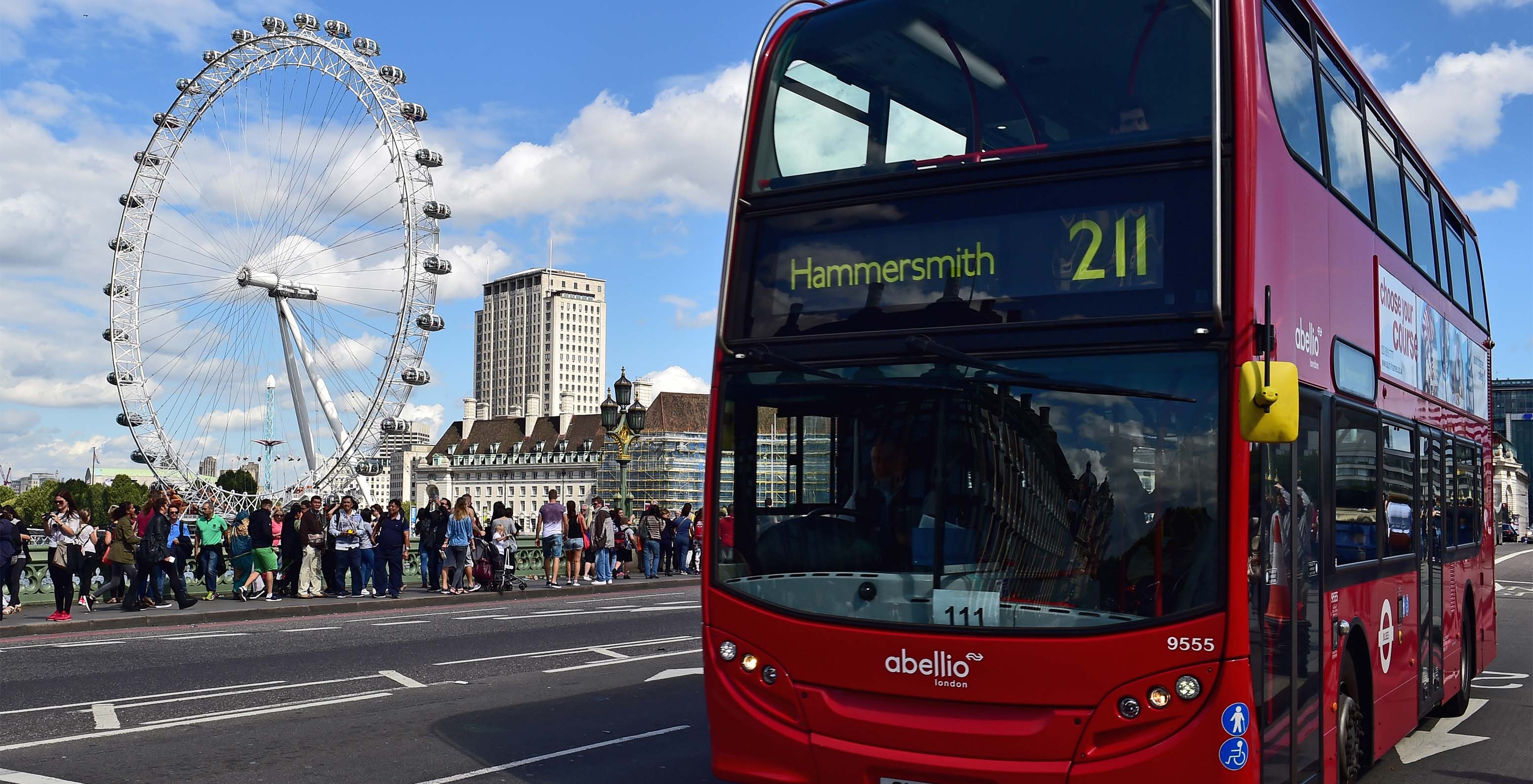 Blick auf das London Eye mit vielen Touristen und einem typischen roten Doppeldeckerbus aus London