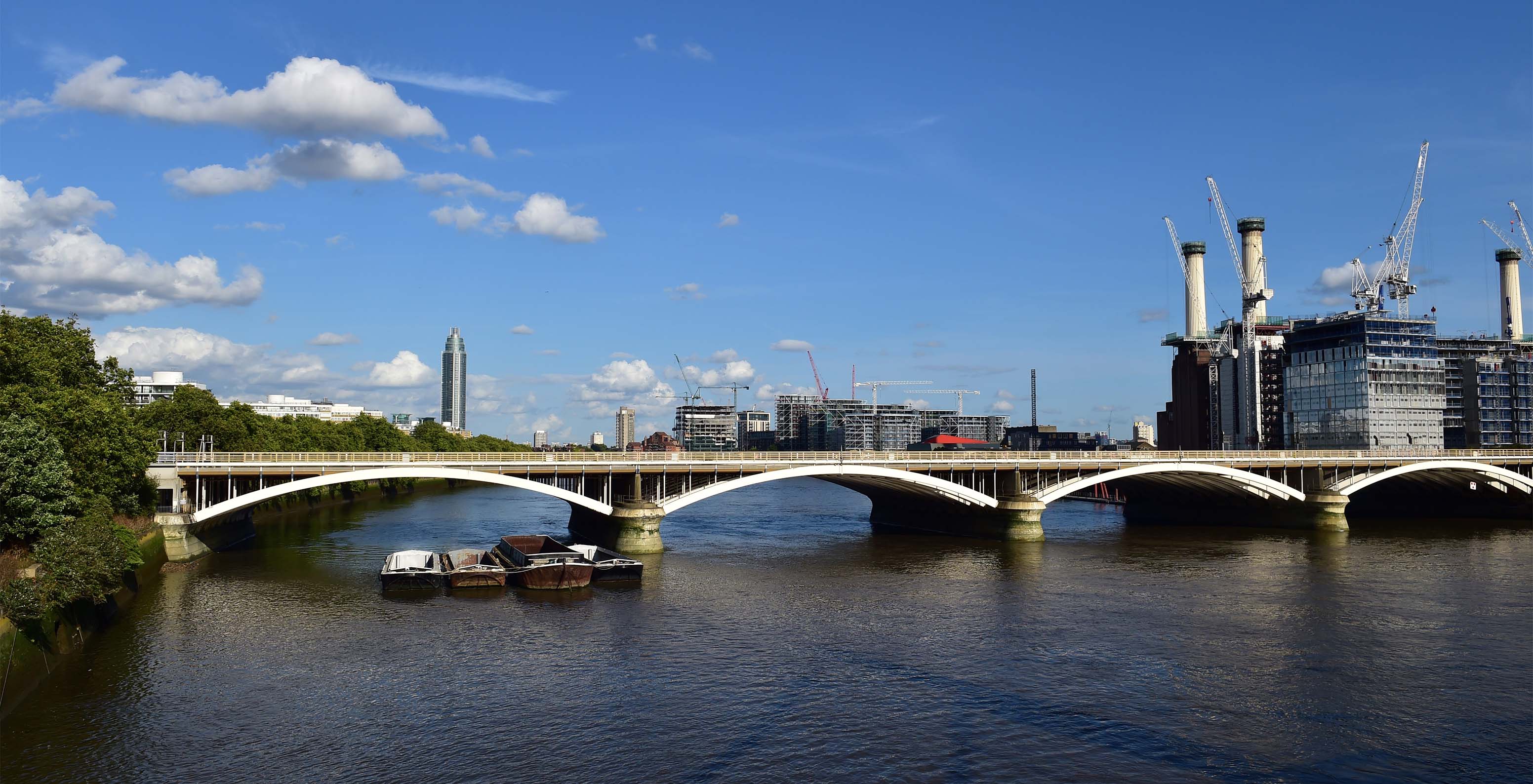 Blick auf eine Brücke, die den Fluss überquert, mit mehreren Gebäuden und Bäumen in der Stadt London