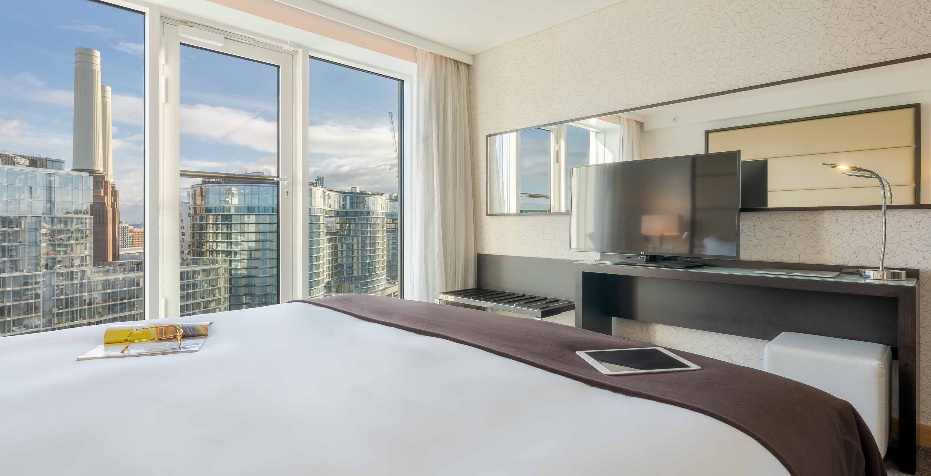 Die Signature Suite im Pestana Chelsea Bridge hat ein Doppelbett, Schreibtisch mit Fernseher und Blick auf die Stadt