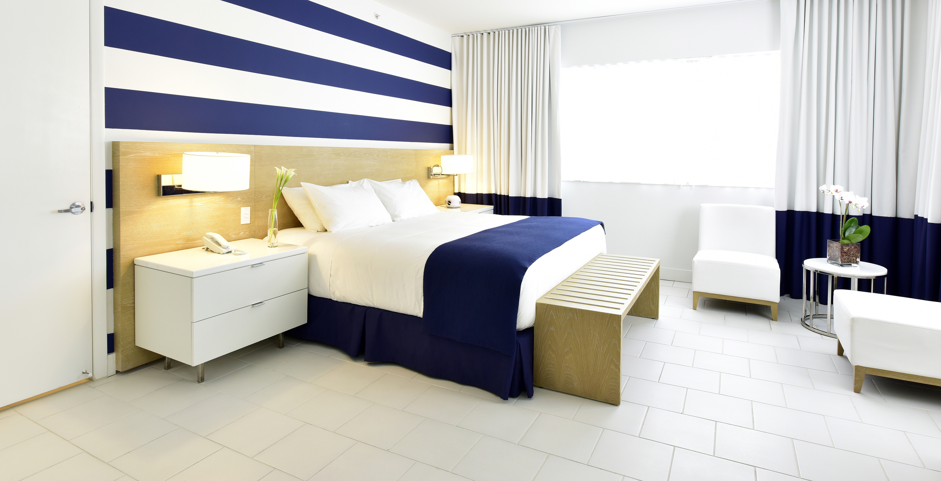 Das Deluxe King - ADA Zimmer im Pestana Miami South Beach hat King-Size-Bett, Lampe, Tisch und zwei Stühle