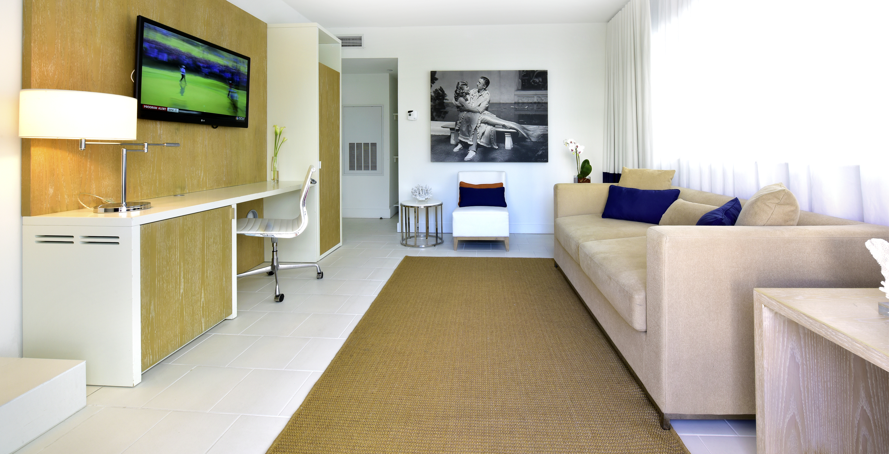 Die Master Suite im Pestana Miami South Beach hat Wohnzimmer mit Sofa, Stuhl, Fernseher und Schreibtisch