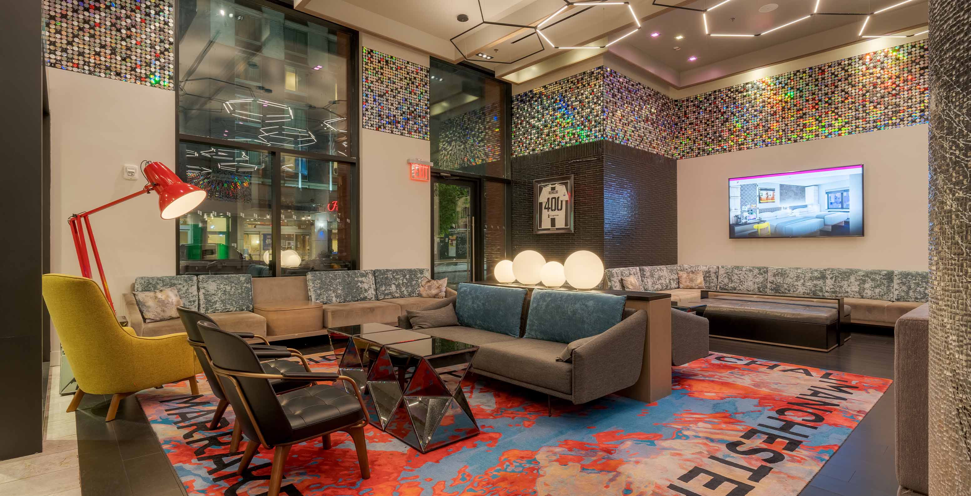 Lobby des Pestana CR7 Times Square mit Sofas, Sesseln, einem Couchtisch und einem Fernseher