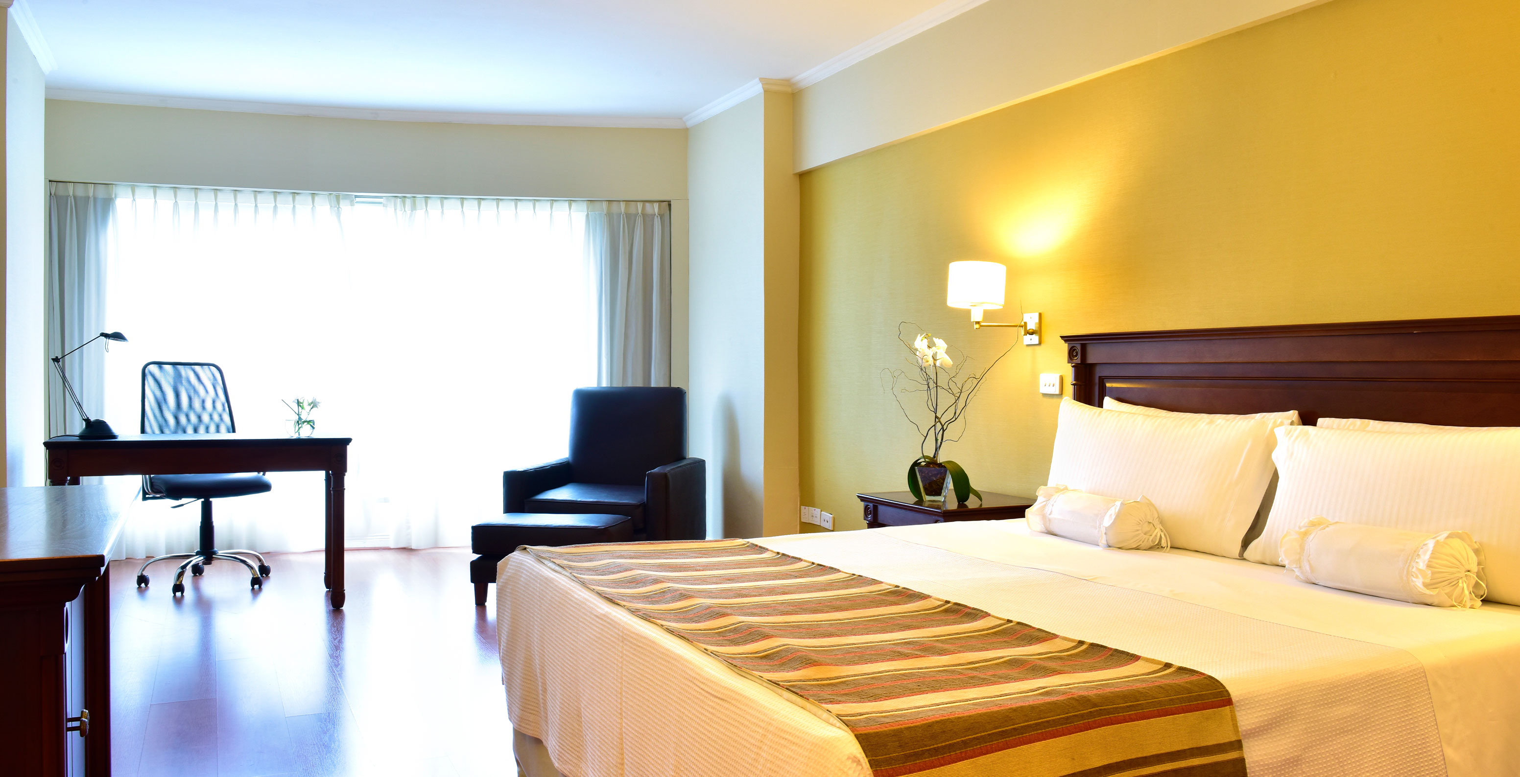 The Queen Superior Room at Pestana Buenos Aires has a double bed, a bedside table, a desk, and a chair