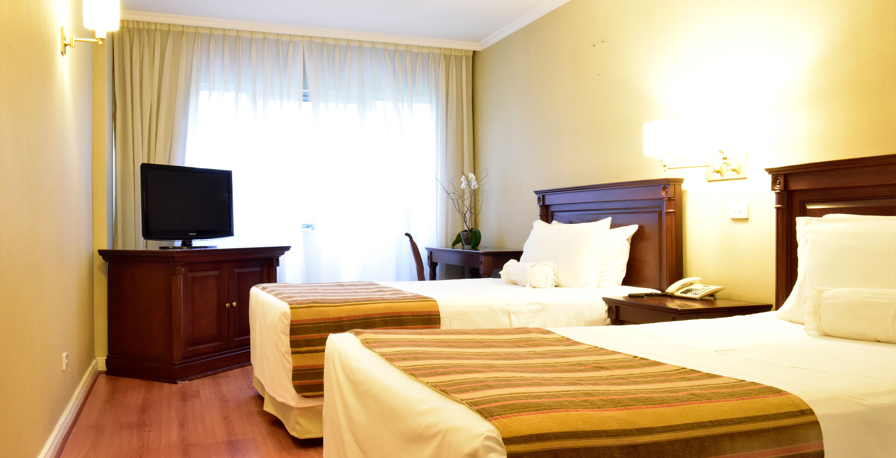 The Twin Deluxe Room at Pestana Buenos Aires has two single beds, a bedside table, TV, and desk