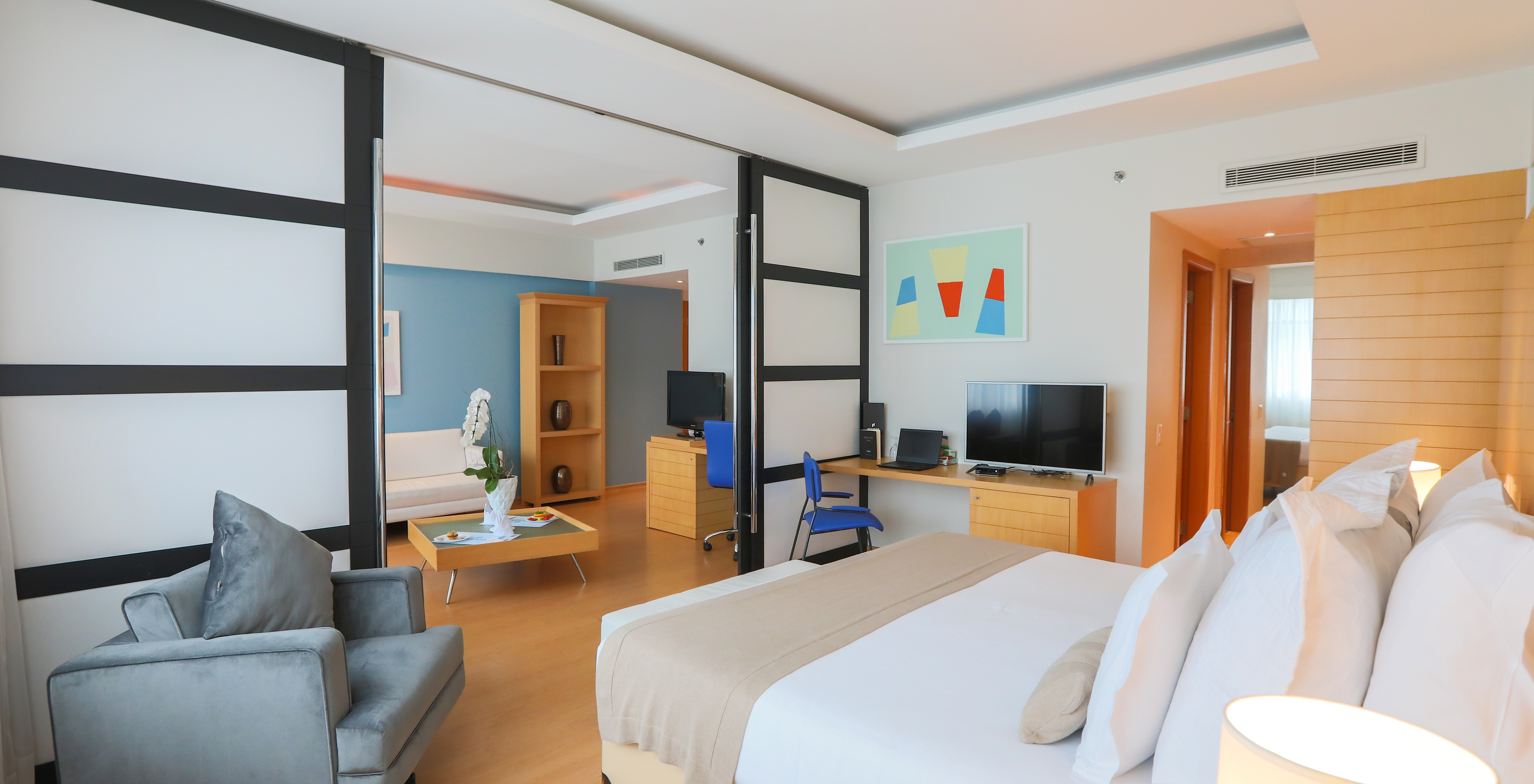 The King Master Suite at Pestana Curitiba has a room with a king-size bed and a large living room with sofa and television