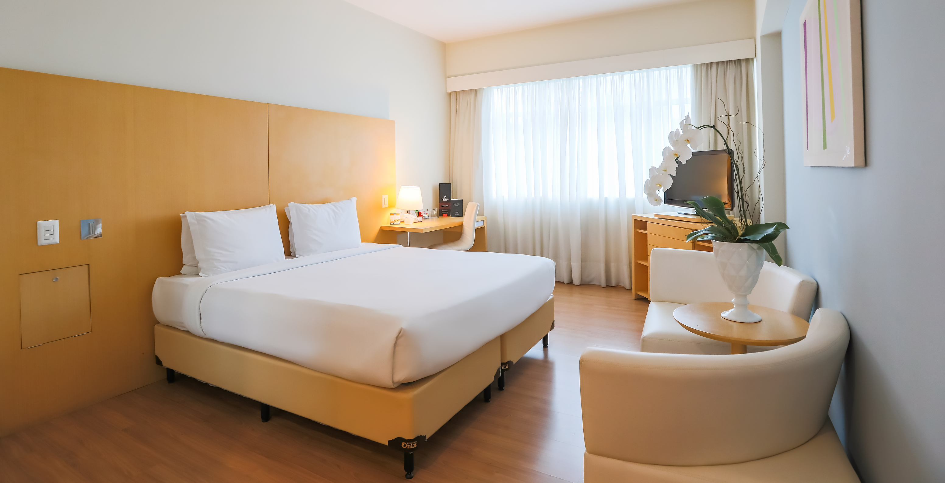 The Queen Superior at Pestana Curitiba has a room with a double bed, sofas, a desk, and a furniture unit with a TV