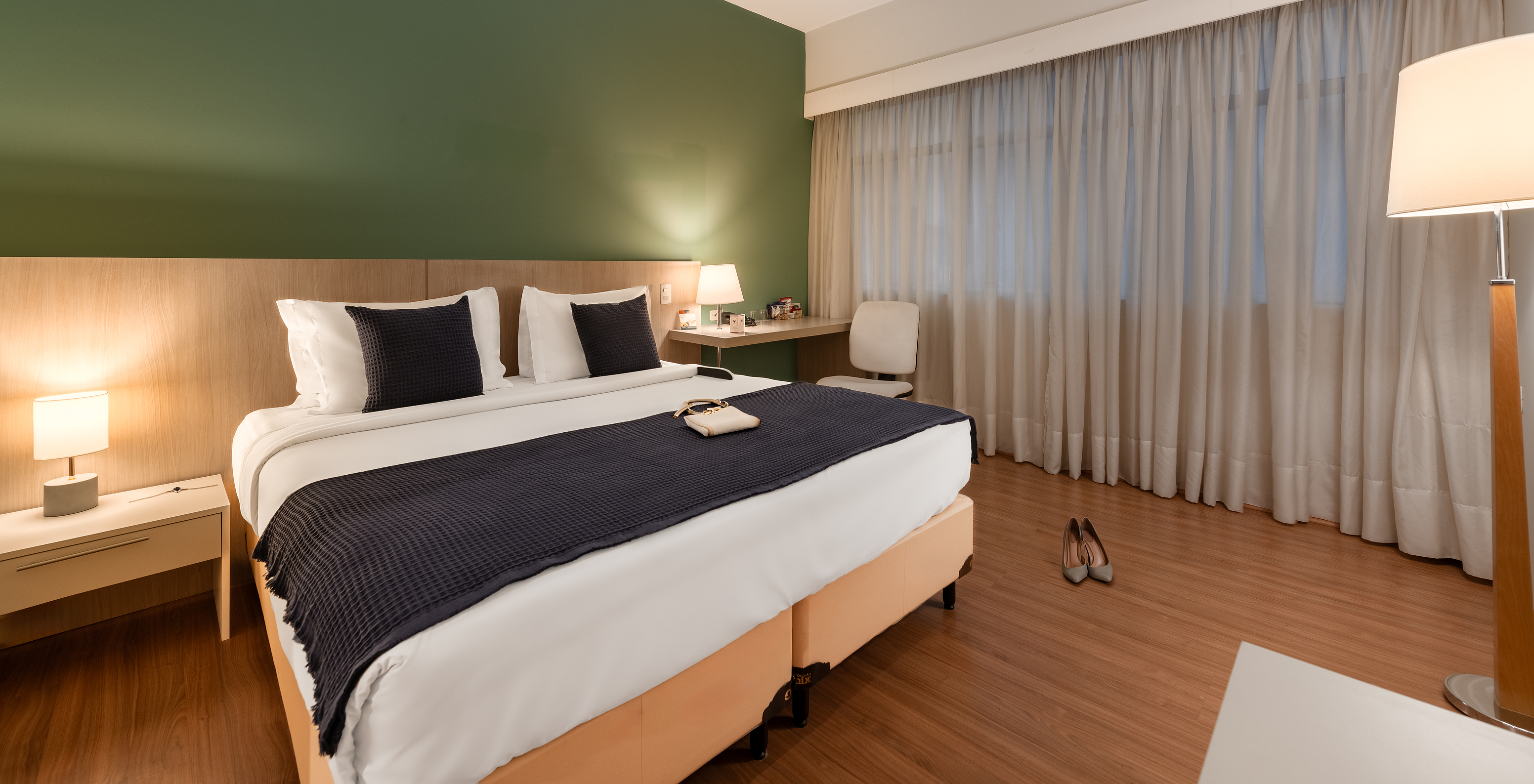 The Adapted Superior at Pestana Curitiba has a bed with a desk and a window beside it