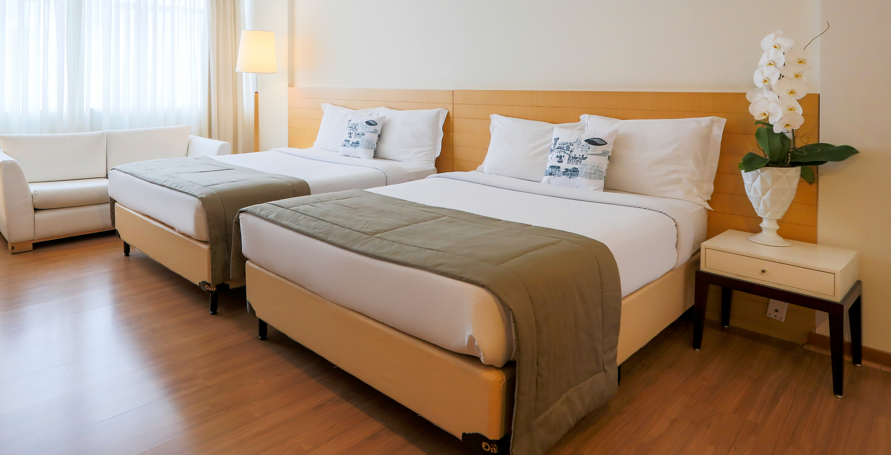 The Twin Superior at Pestana Curitiba has a clean decor in light wood tones, with a double sofa and a window