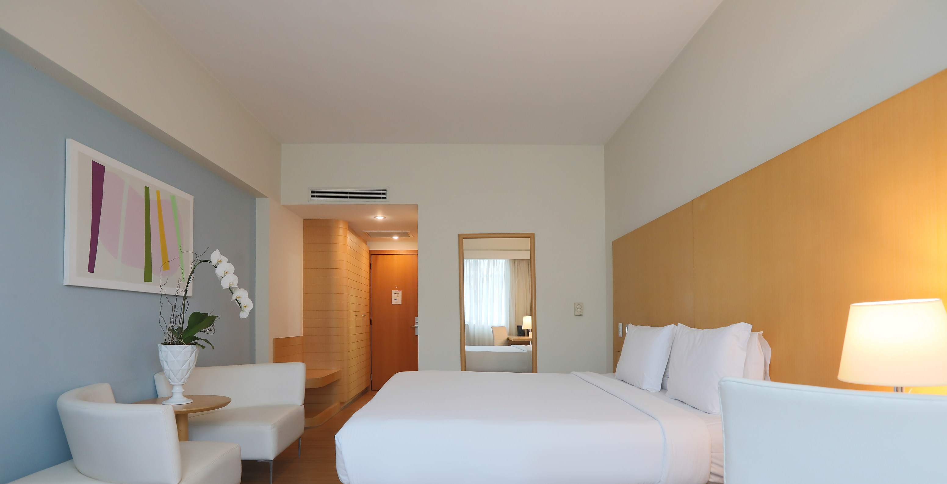 The Queen Superior at Pestana Curitiba has a double bed and two single sofas at the foot of the bed