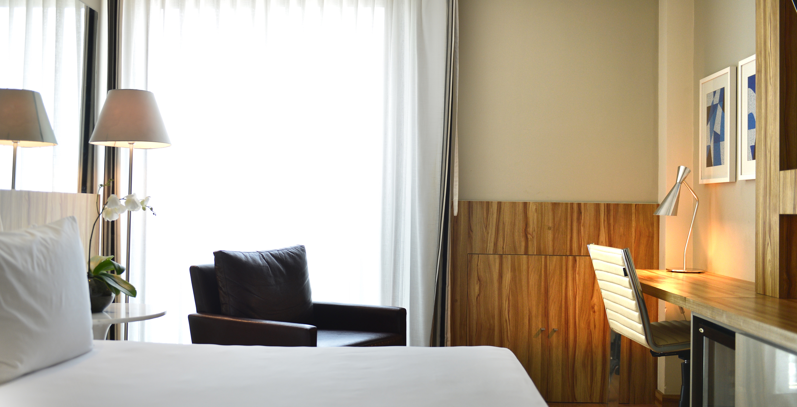 The Standard Twin Room of Pestana Rio Atlântica has a double bed, an armchair, and a desk with a comfortable chair