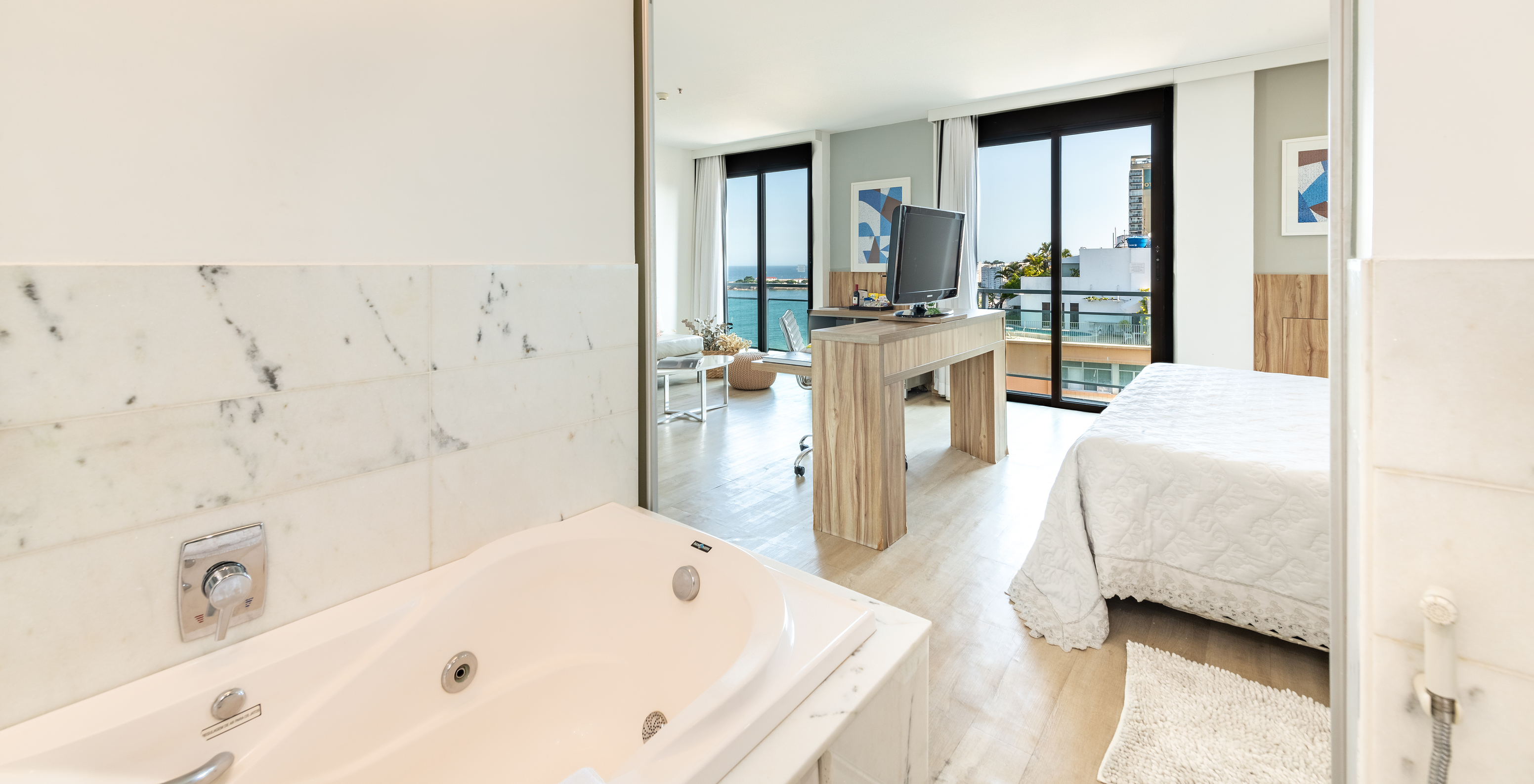 The Junior Suite of Pestana Rio Atlântica has a bathroom with a bathtub and a bedroom with television