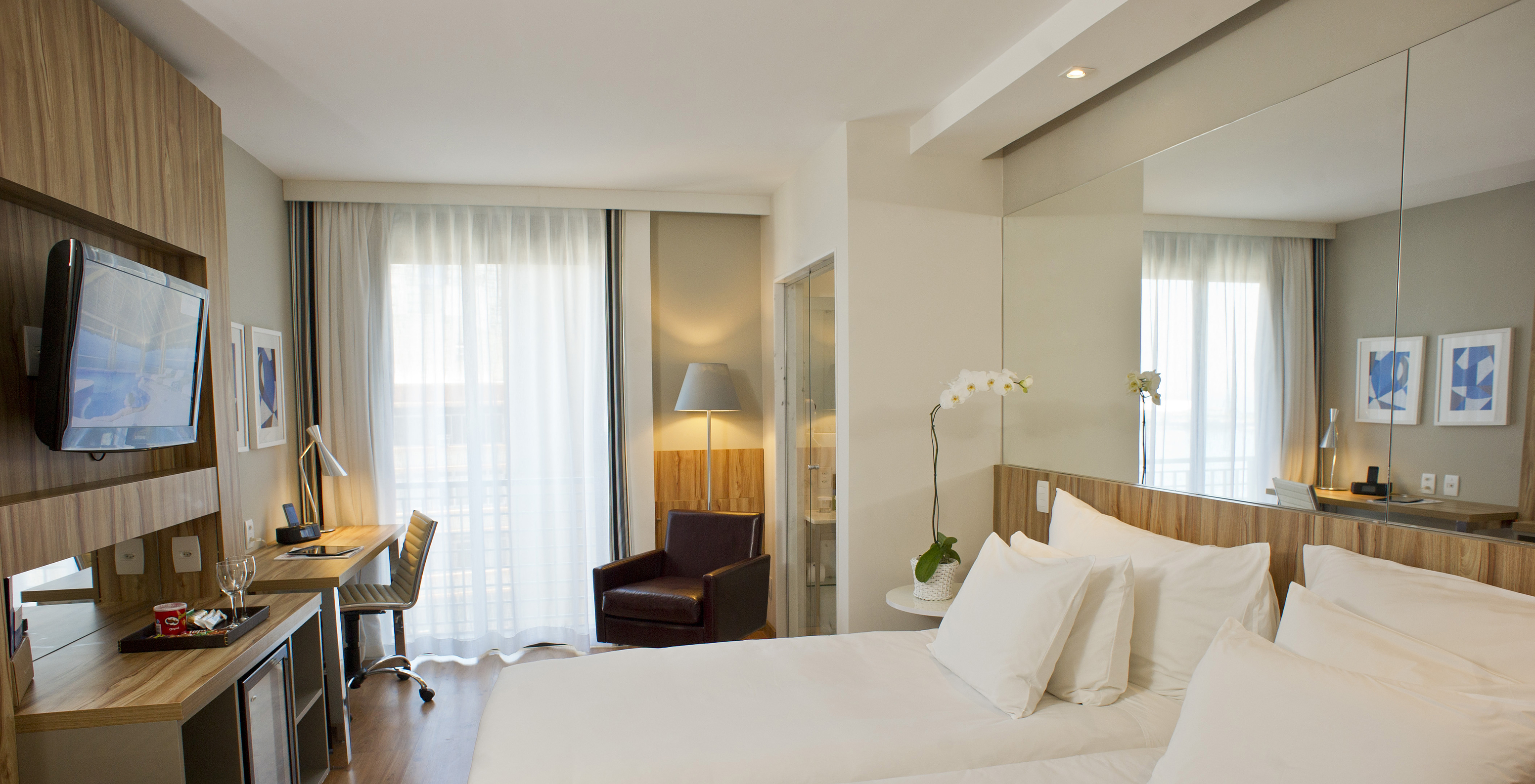 The Lateral Sea View Twin Room of Pestana Rio Atlântica has two beds with a mirror on the headboard and a television in front