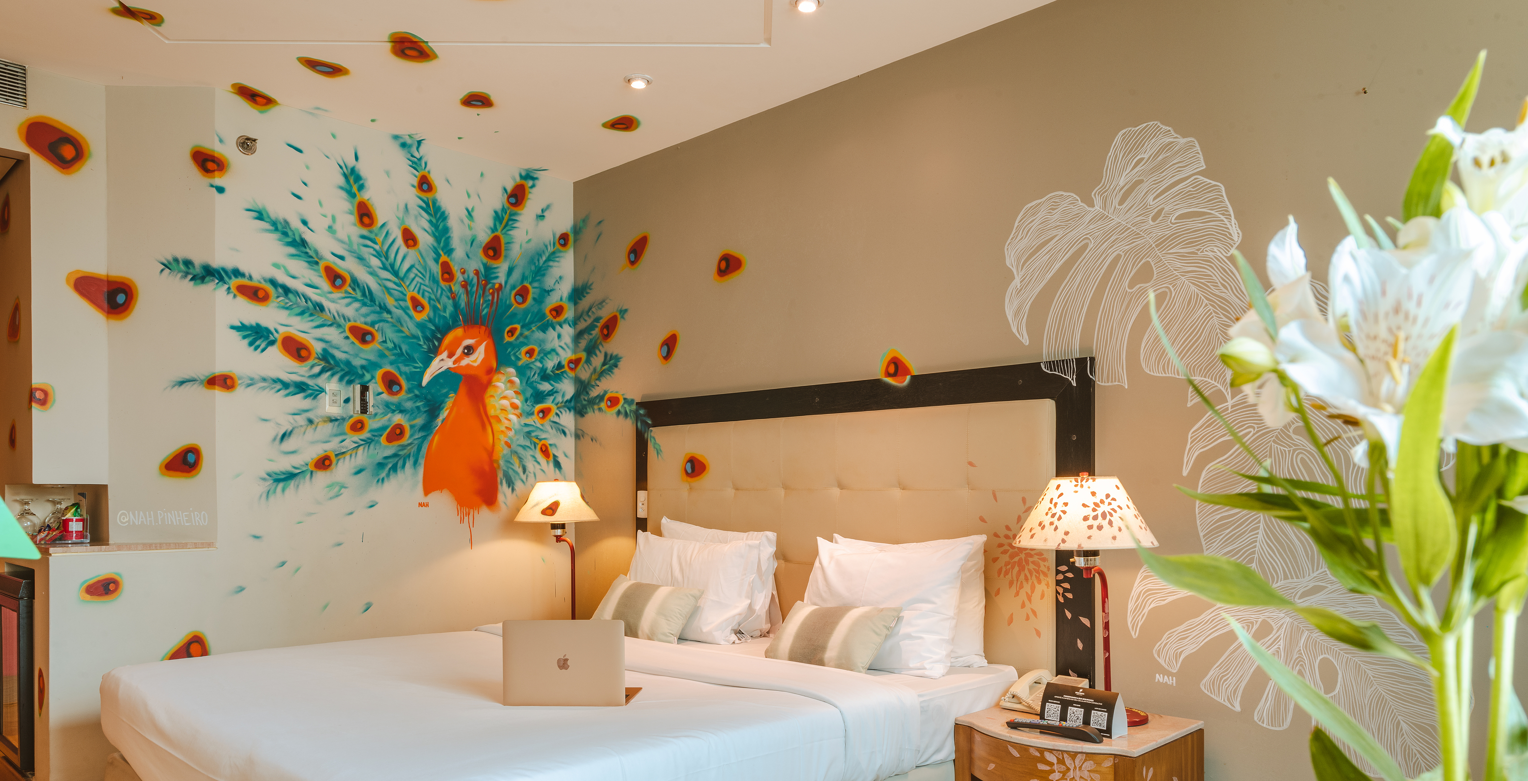 Room decorated by artist Nah Pinheiro with a colorful peacock on the wall in a 4-star hotel in São Paulo