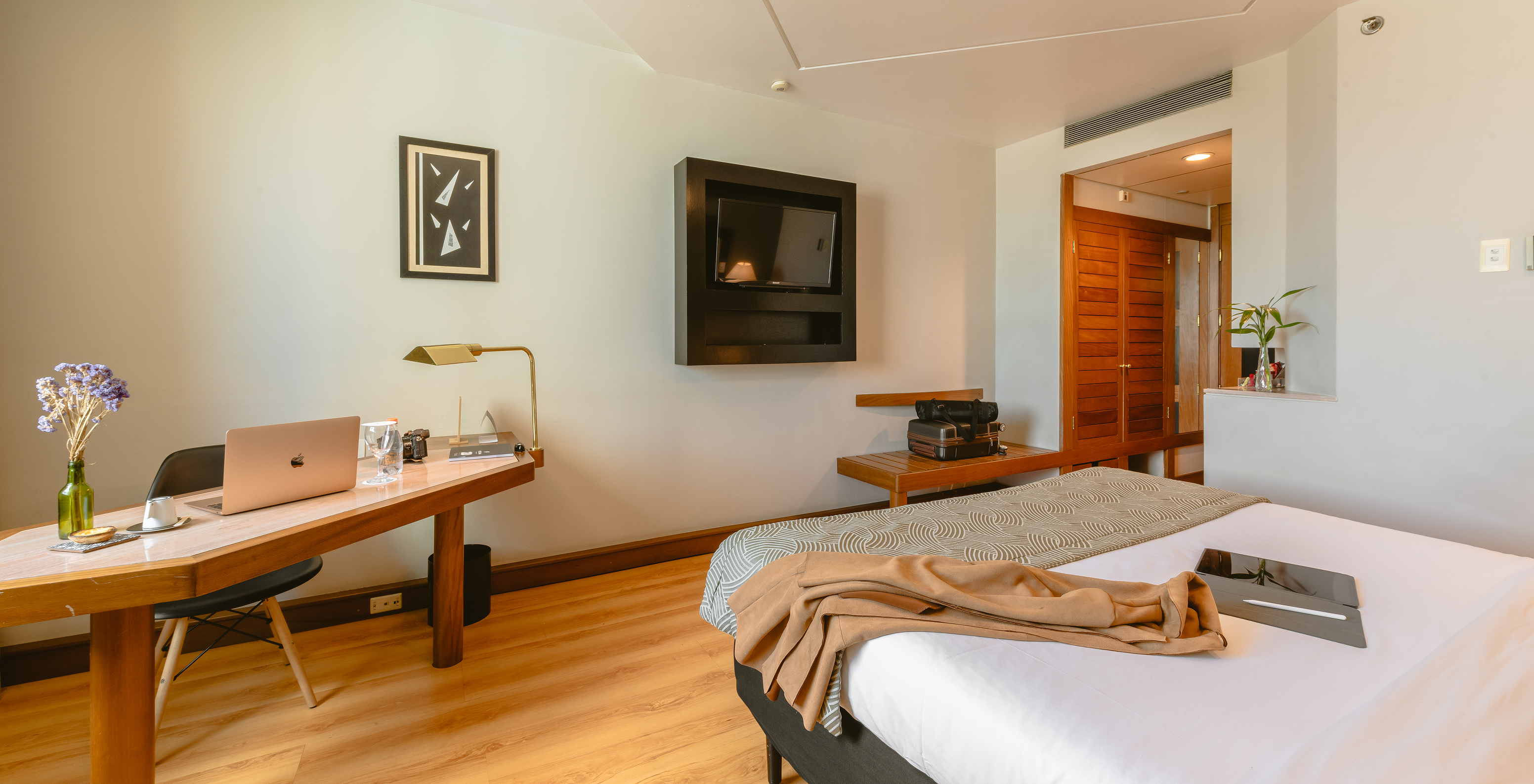 The Standard Room of Pestana São Paulo has a corridor at the entrance, a television at the foot of the bed, and a desk