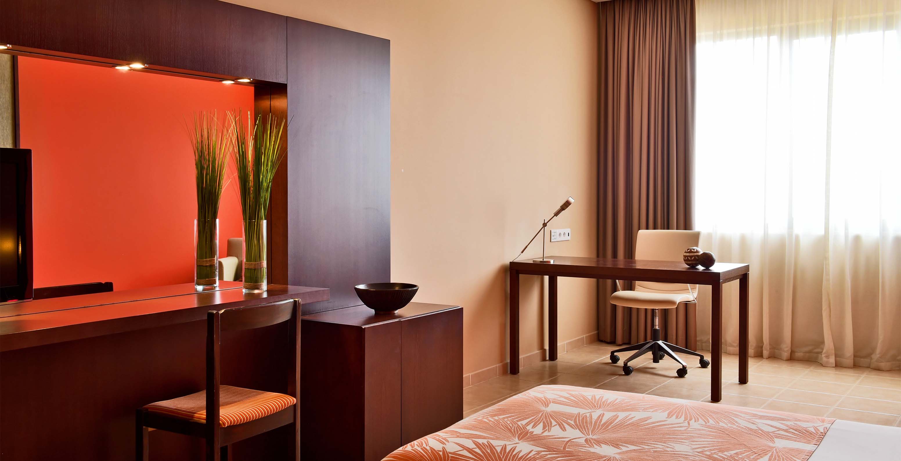 The Classic Sea View room at Pestana Tropico features a desk with lamp and a chair, bed, and a mirror