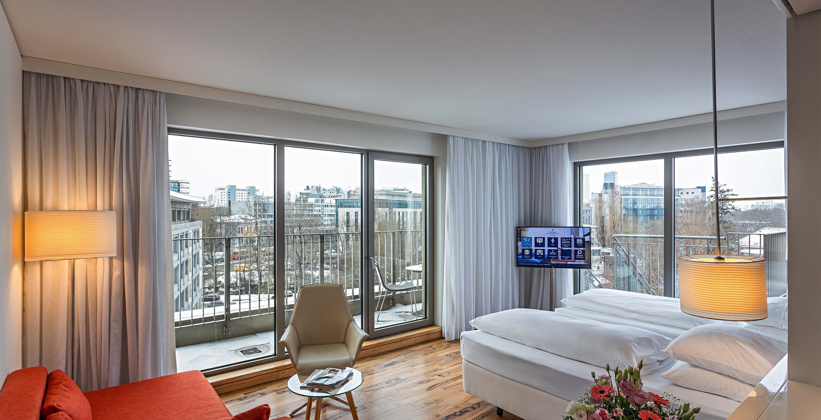 Premium Room with Panoramic Balcony at Pestana Berlin Tiergarten has a sofa with lamp, TV and bed