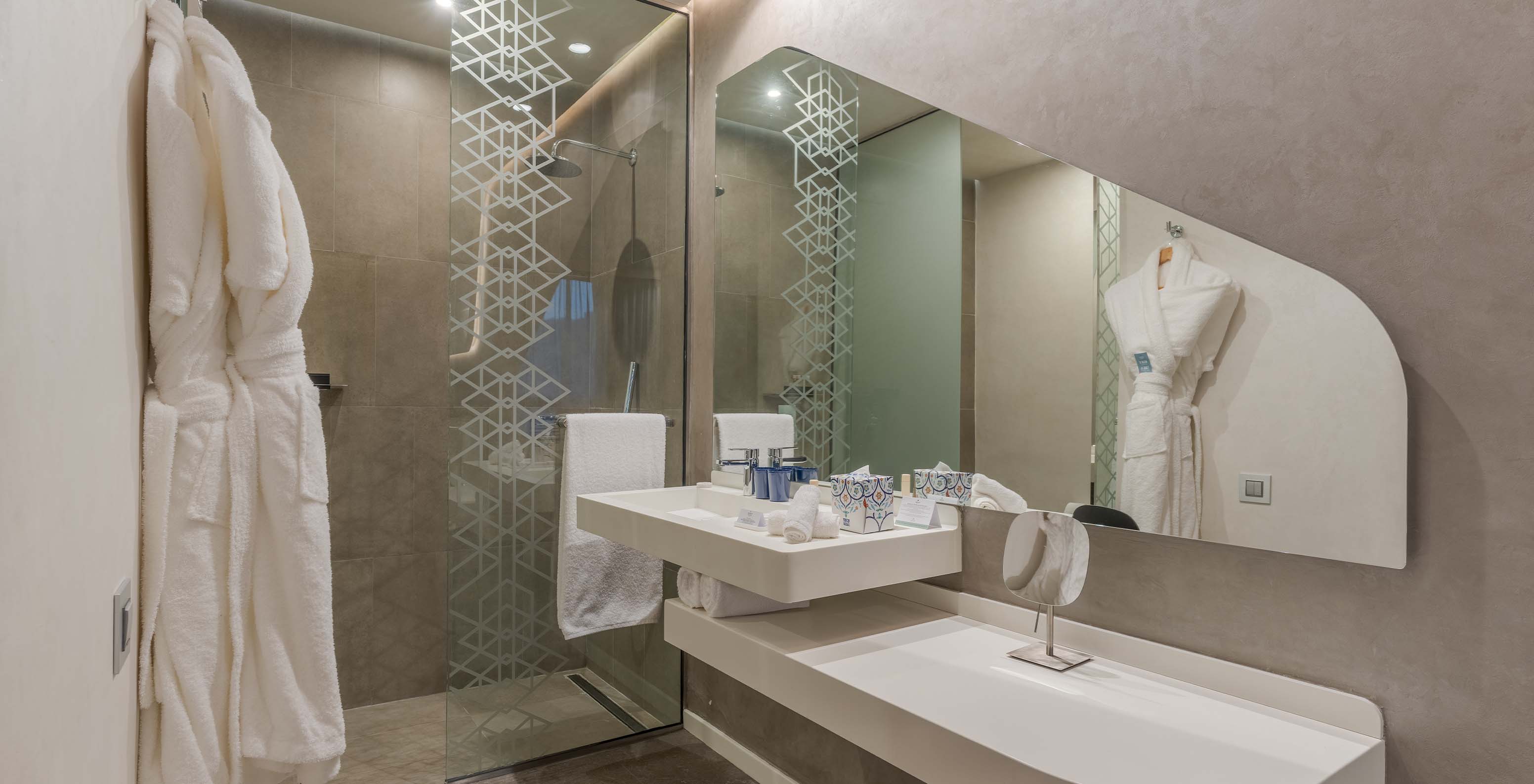 The CR7 Junior Suite Avenue at Pestana CR7 Marrakech has a bathroom with a sink, mirror, walk-in shower, and amenities