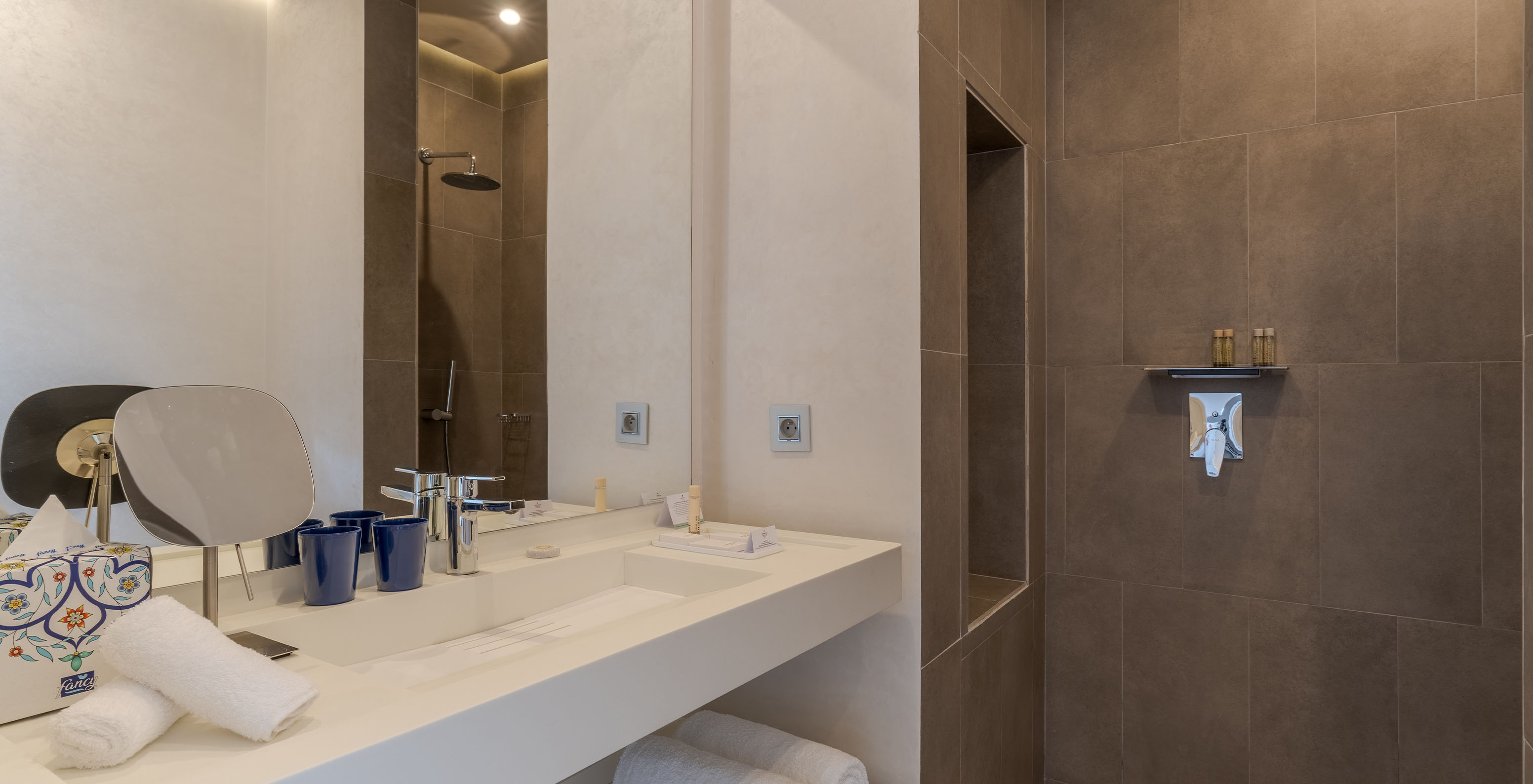 The CR7 Suite at Pestana CR7 Marrakech has a bathroom with a walk-in shower and a sink with a large mirror