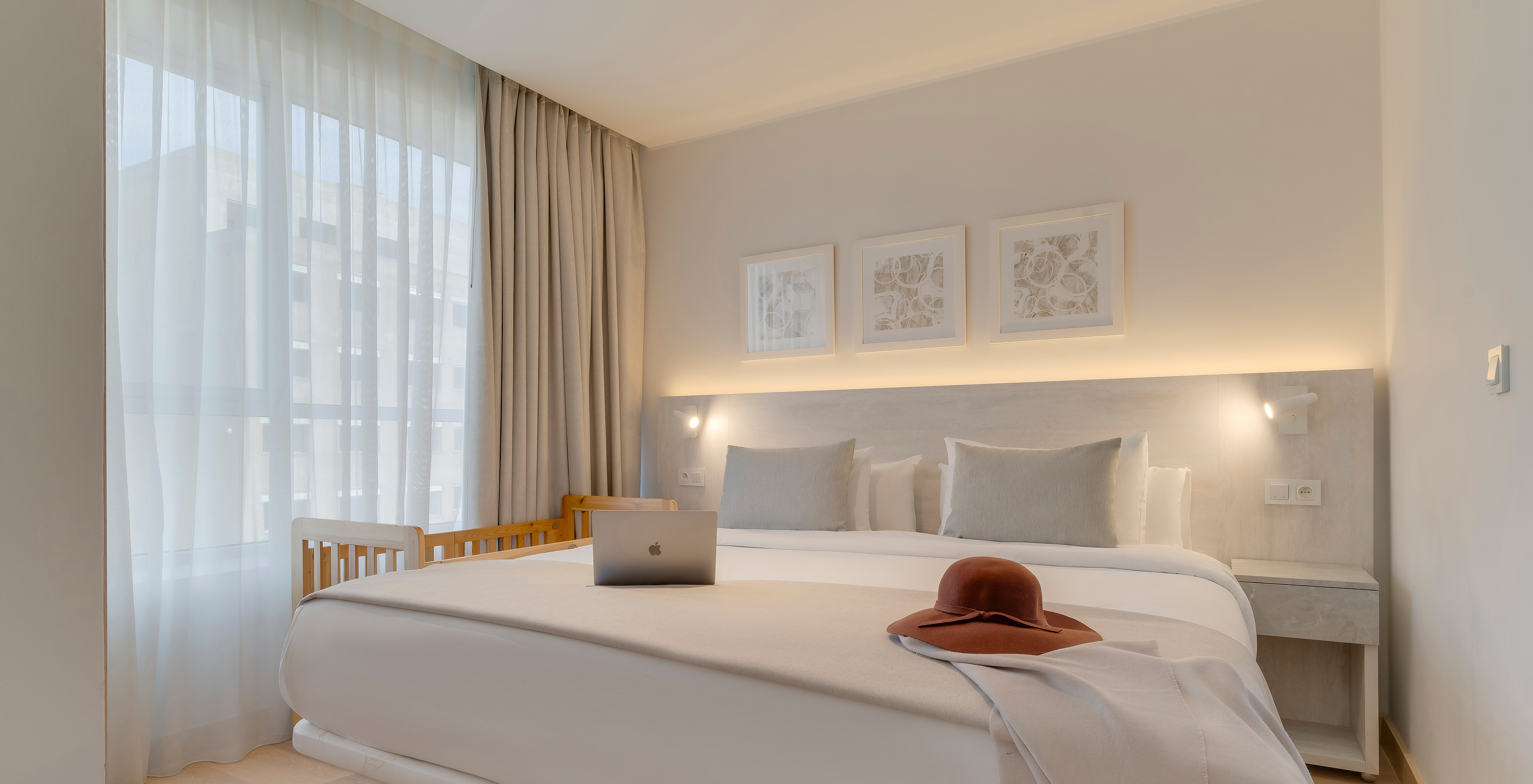 The Suite of Pestana Tanger City Center features a double bed with stone headboard, a crib beside it, and a window