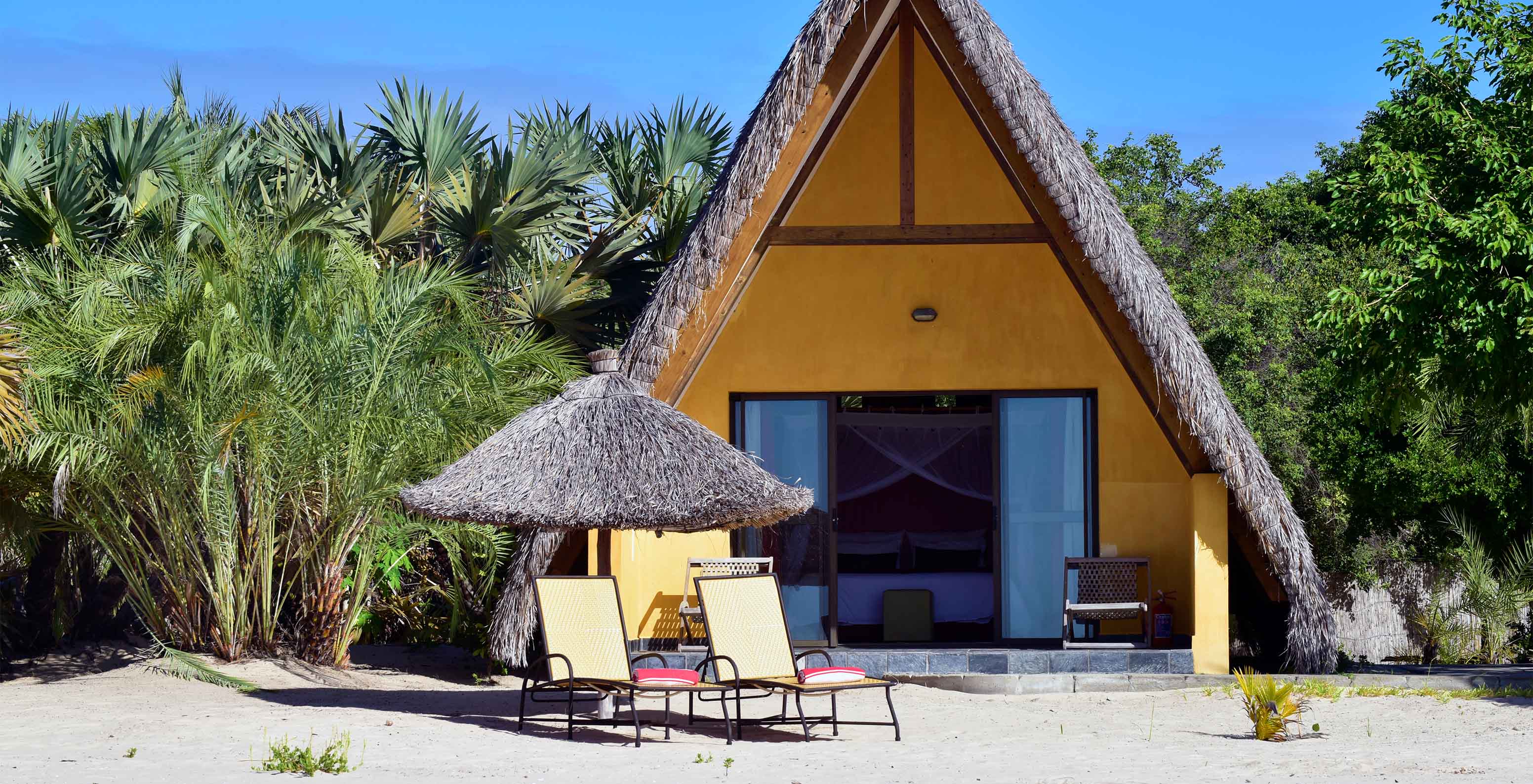 Bungalow T1 at Pestana Bazaruto Lodge is a yellow house on the beach with a thatched roof and A-shape