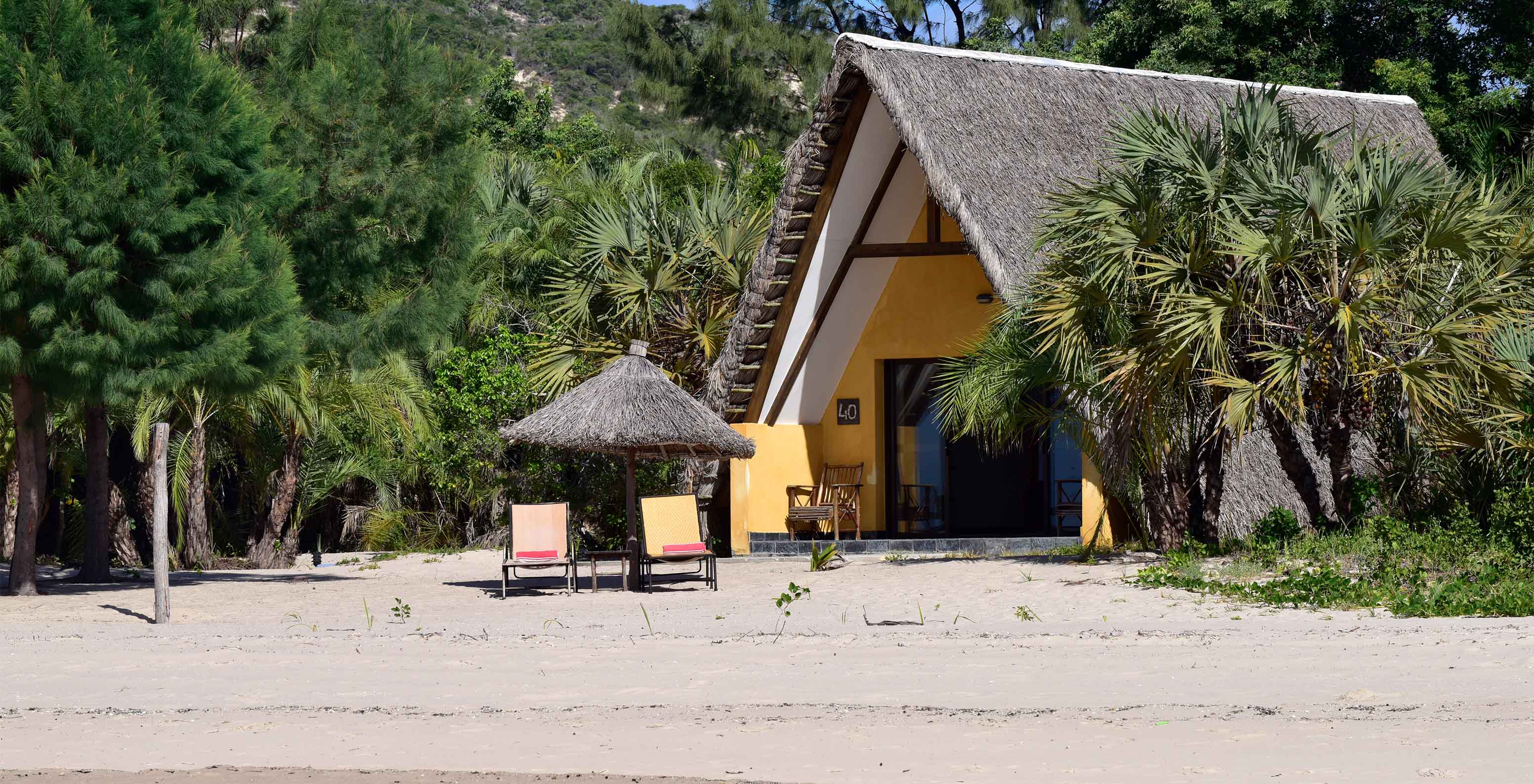 Bungalow Suite T2 at Pestana Bazaruto Lodge is a small house with a thatched roof on the beach, surrounded by greenery