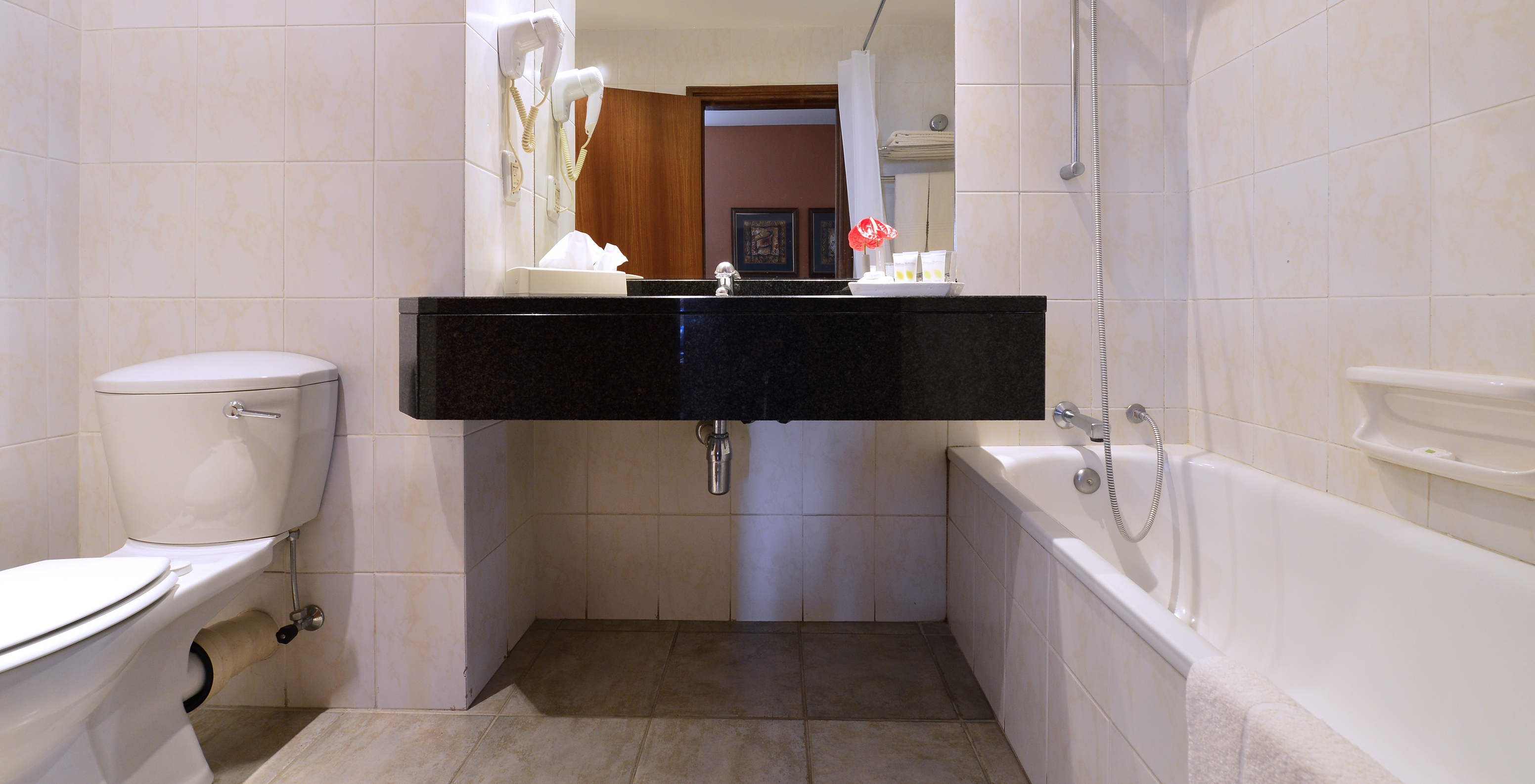 The Executive Double of Pestana Rovuma has a bathroom with bathtub with shower, sink with mirror, and a toilet