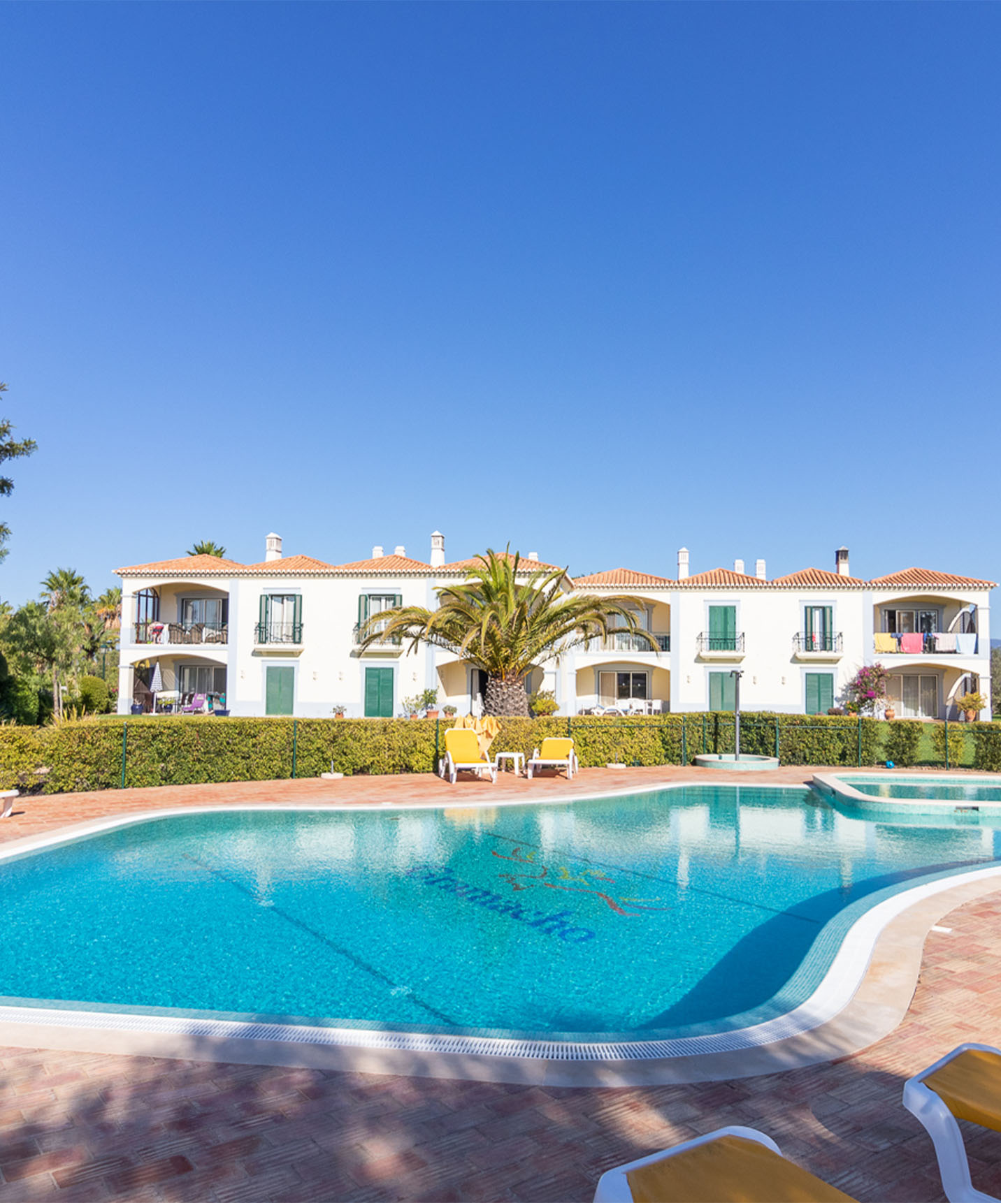 Common outdoor pool with several yellow loungers at Pestana Carvoeiro hotel near golf courses