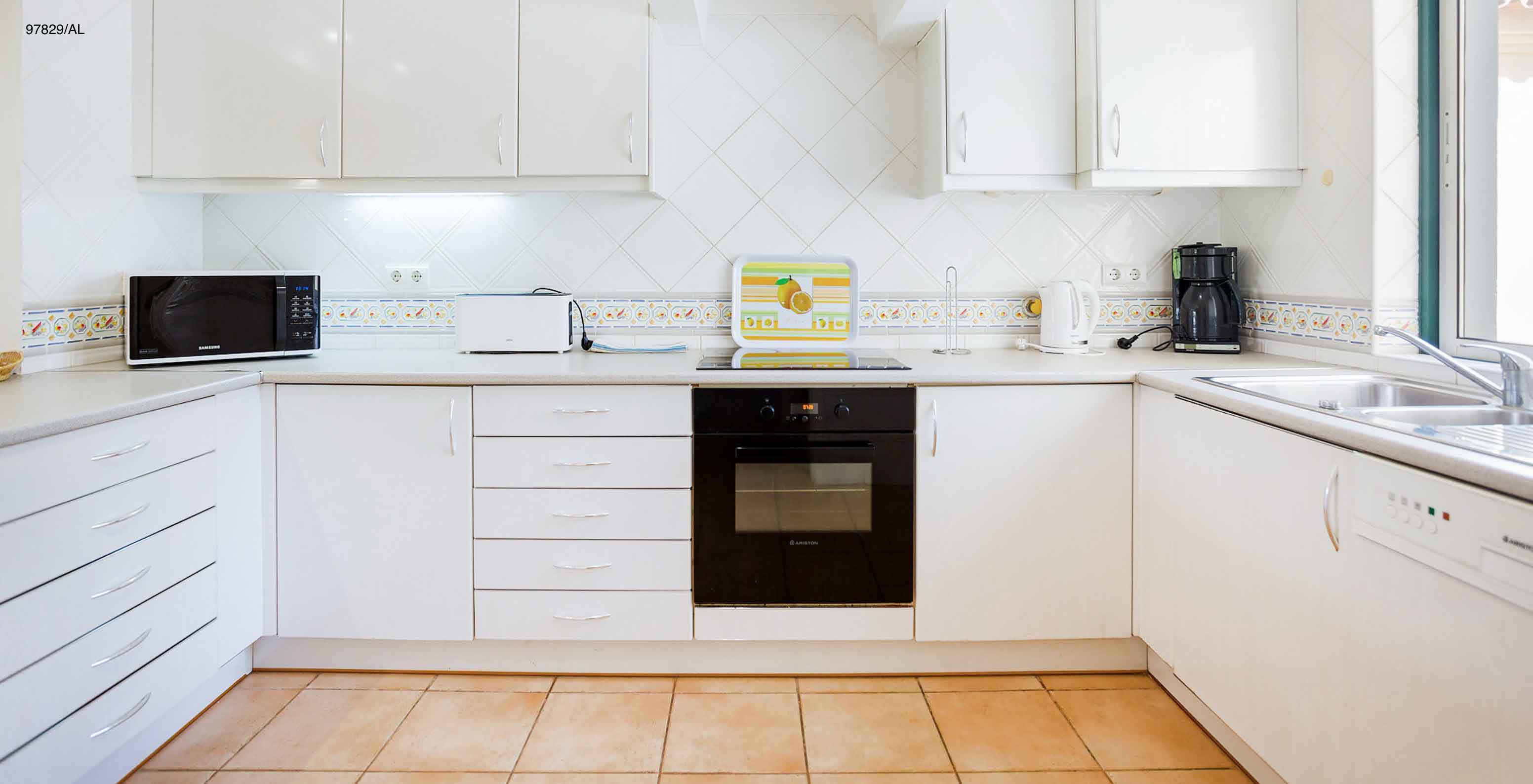 The Pestana Carvoeiro Golf T2 Standard Apartment has a kitchen with white cabinets and a countertop