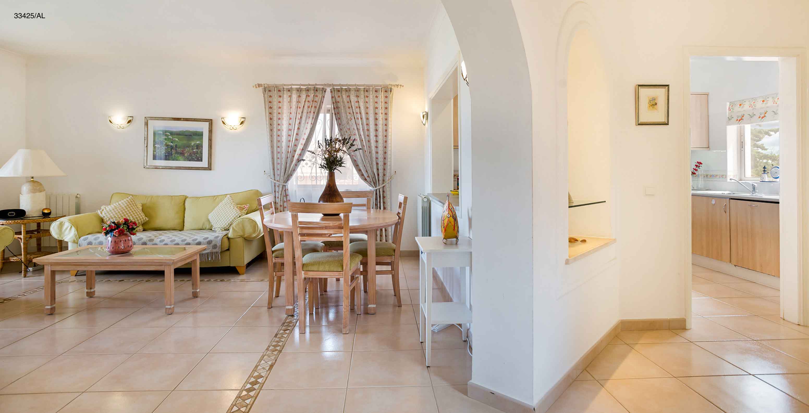 The Pestana Carvoeiro Golf T2 Standard Apartment has a living room with a green sofa and a table with chairs