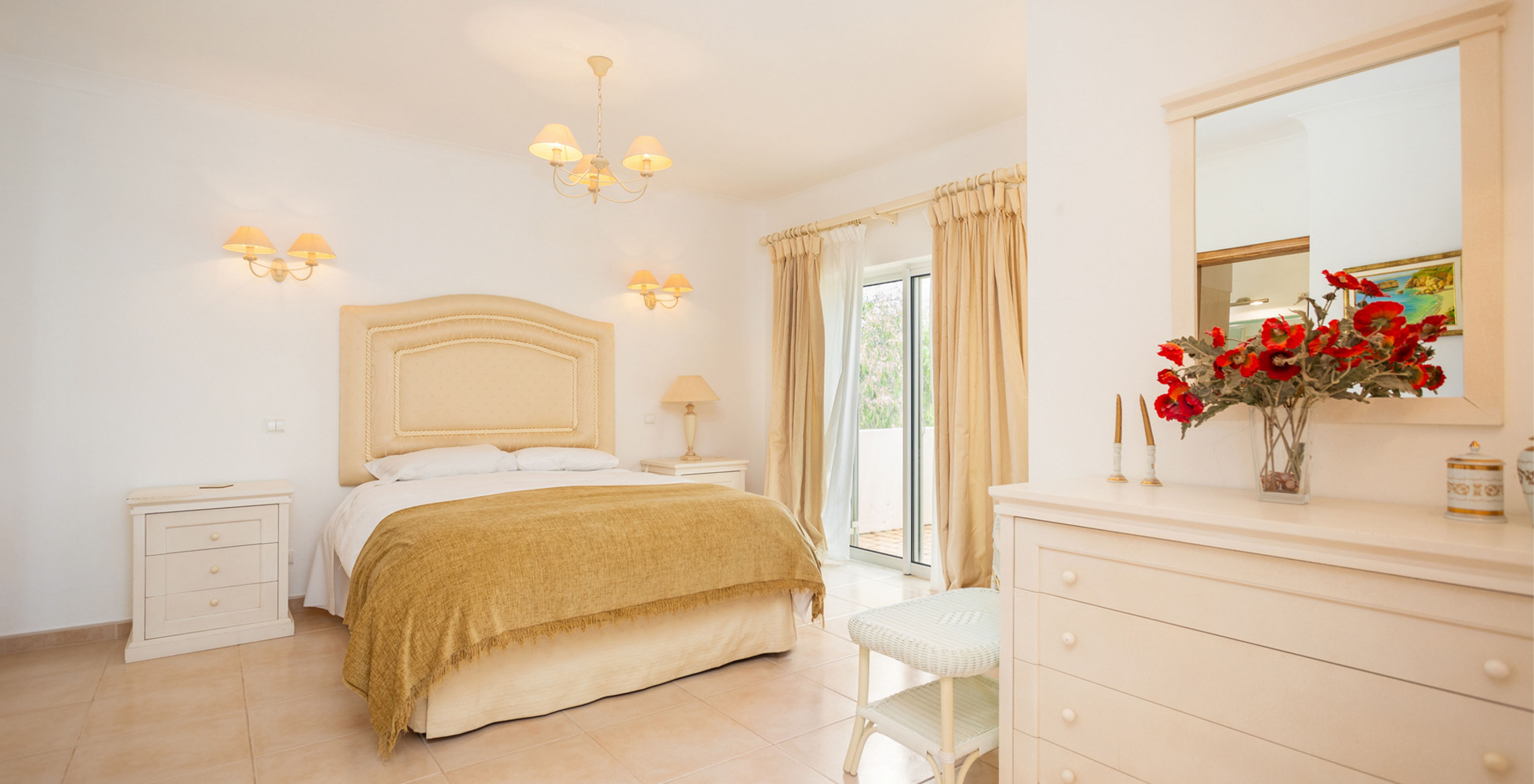 The V3 Villa at Pestana Carvoeiro Golf has a spacious bedroom with a double bed, dresser, mirror, and balcony