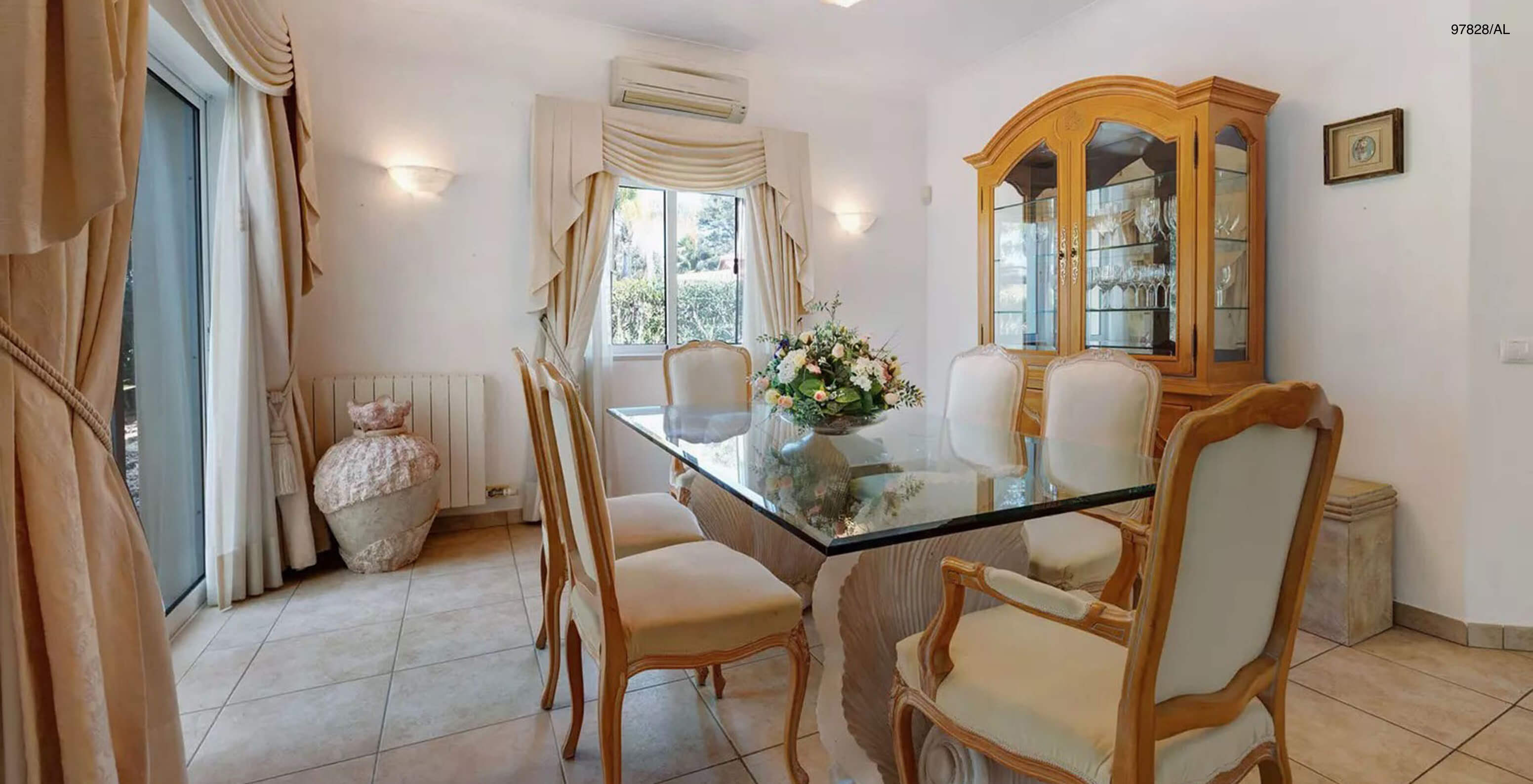 The Pestana Carvoeiro Golf V3 Standard Villa has a dining room with a glass table, chairs, and a cabinet