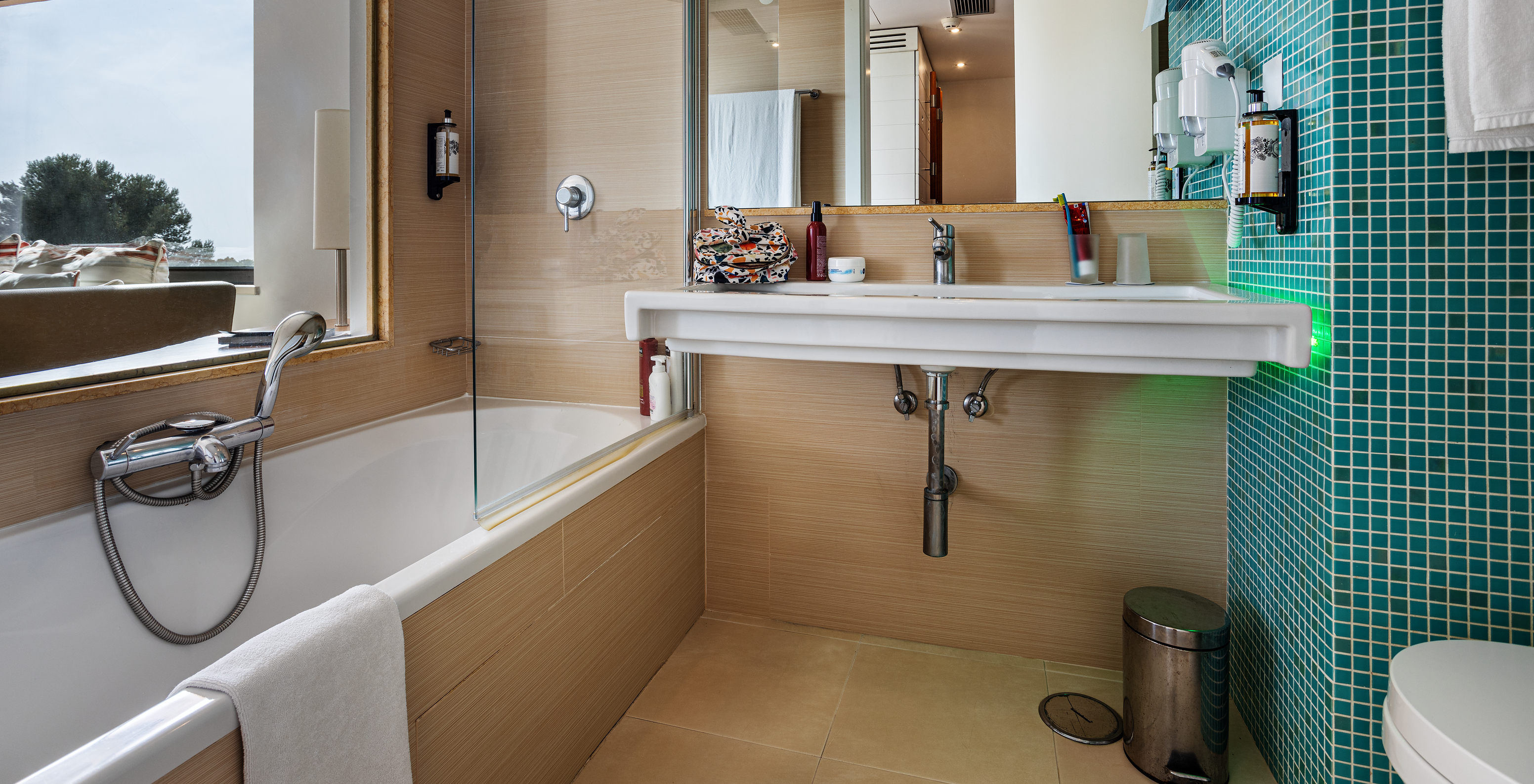 The Deluxe Garden View room at Pestana Dom João II features a bathroom with a sink, mirror, and bathtub