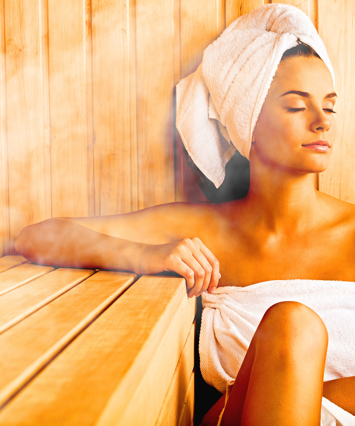 Smiling girl with a towel and closed eyes relaxes in the sauna at a hotel with a pool located in a golf course