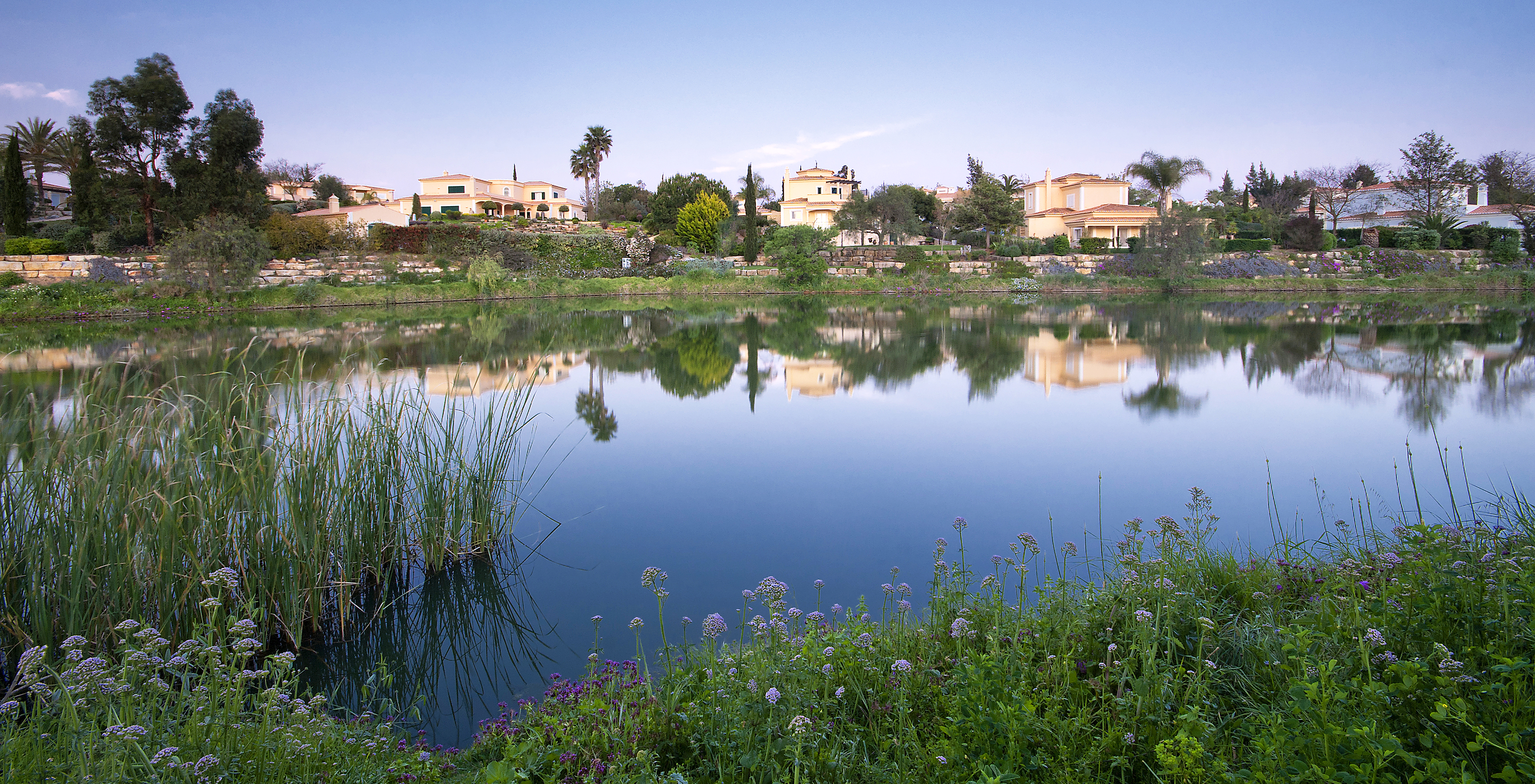 Large lake beside apartments at Pestana Gramacho Residences, surrounded by vegetation