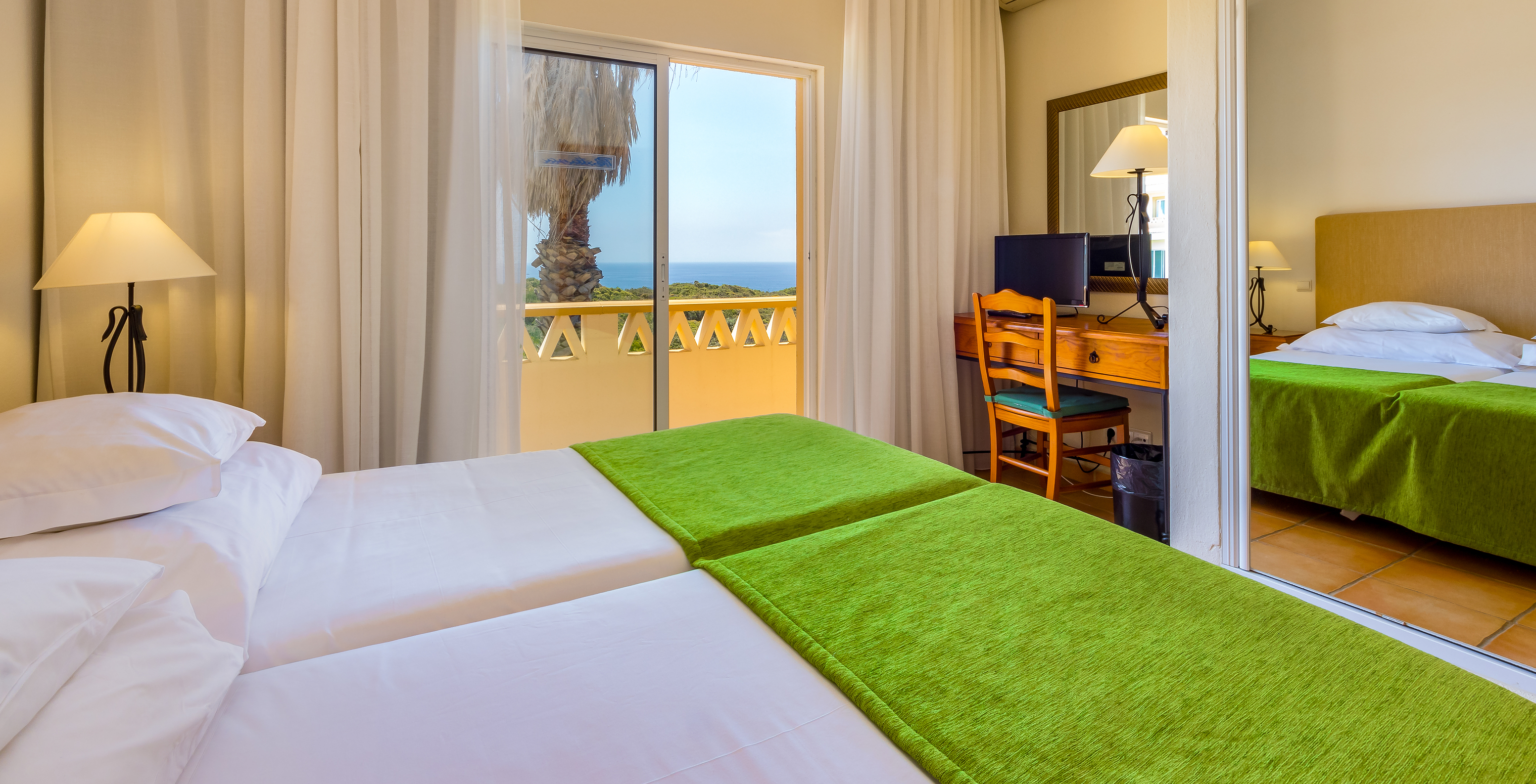 The T2 Apartment Premium do Pestana Palm Gardens has two beds with a green bedspread and a balcony with sea view