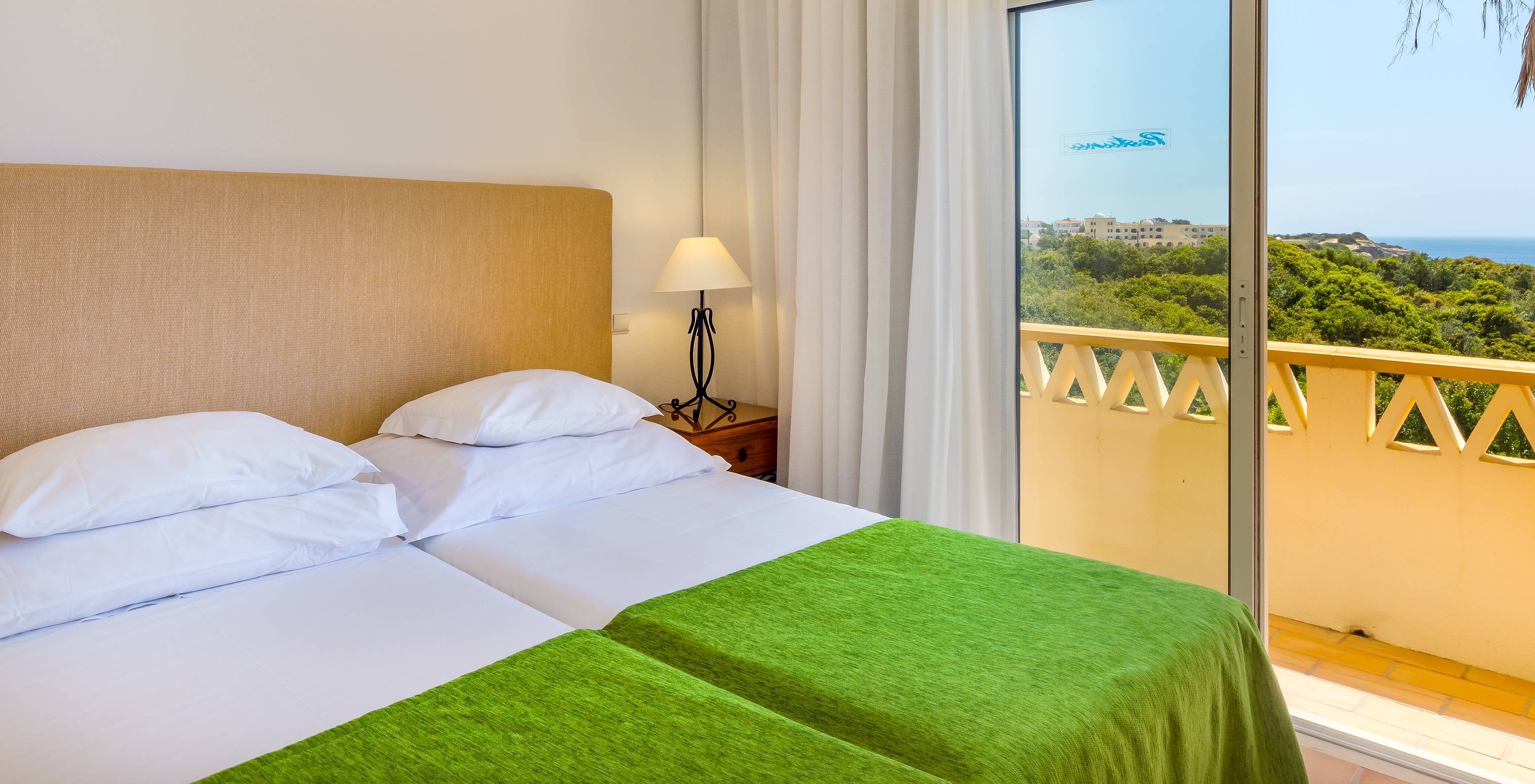 The T2 Apartment Superior do Pestana Palm Gardens has two beds together with a green bedspread and a balcony with sea view