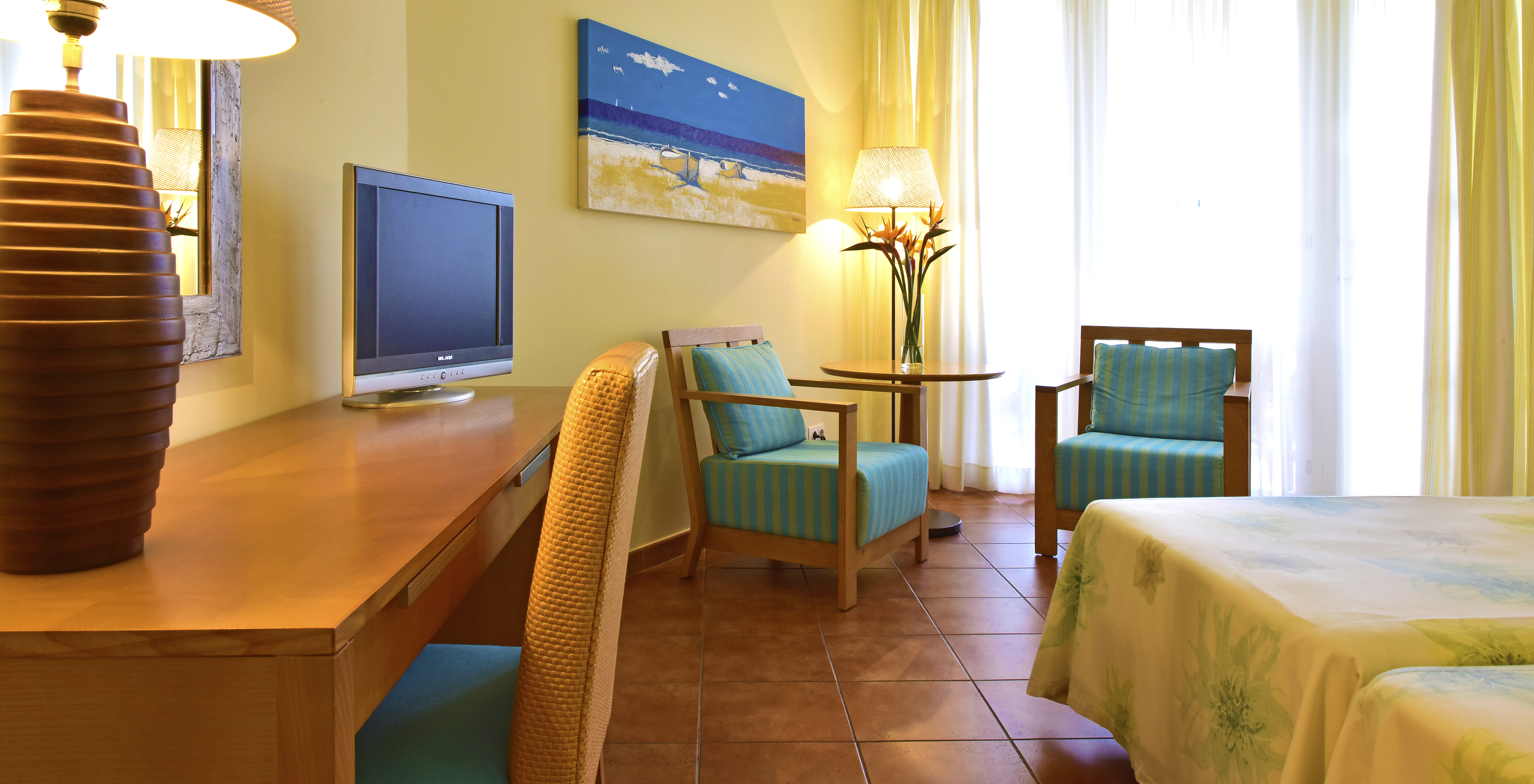 The Deluxe Garden View room at Pestana Viking features television, two chairs with coffee table, and a desk