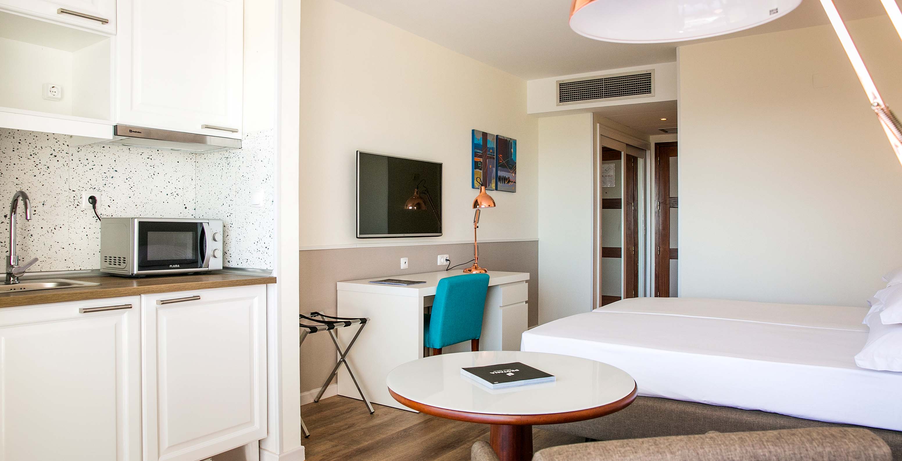 The Deluxe room at Pestana Cascais has two single beds, a TV, a desk, and a kitchenette