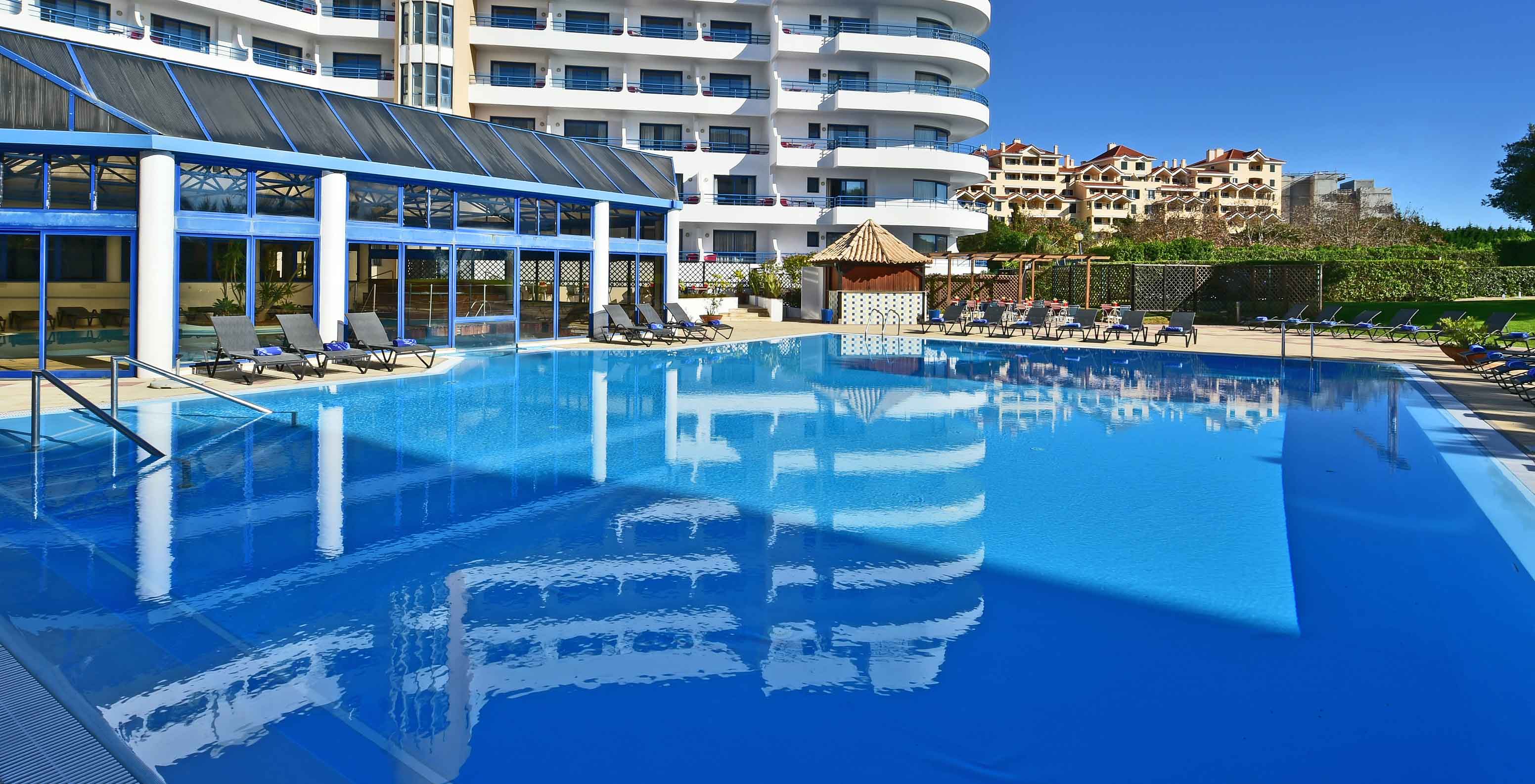 The Pestana Cascais, a hotel by the sea with a pool and spa, has an outdoor pool with sun loungers around it.