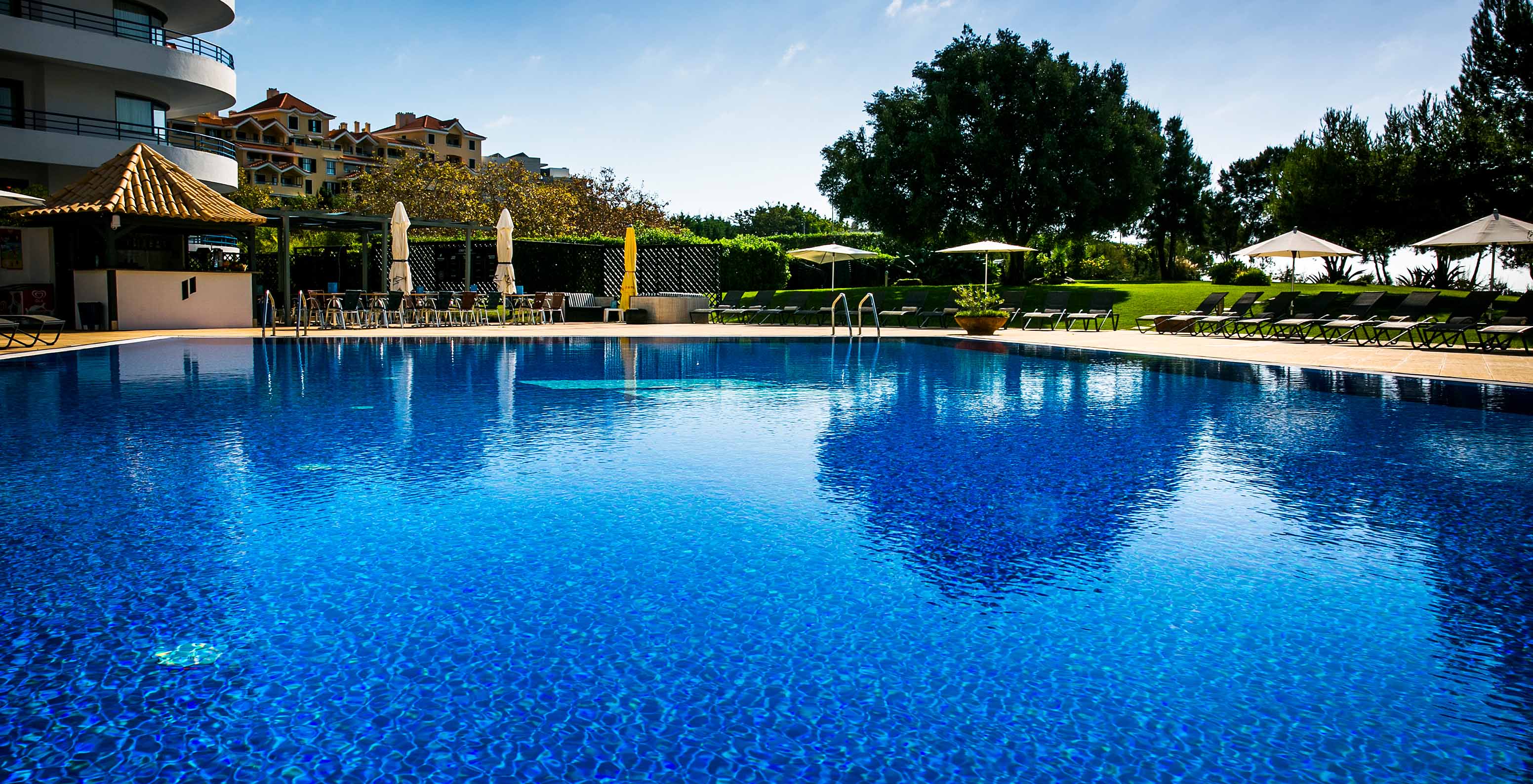 Outdoor pool with loungers in the gardens at Pestana Cascais, facing the sea